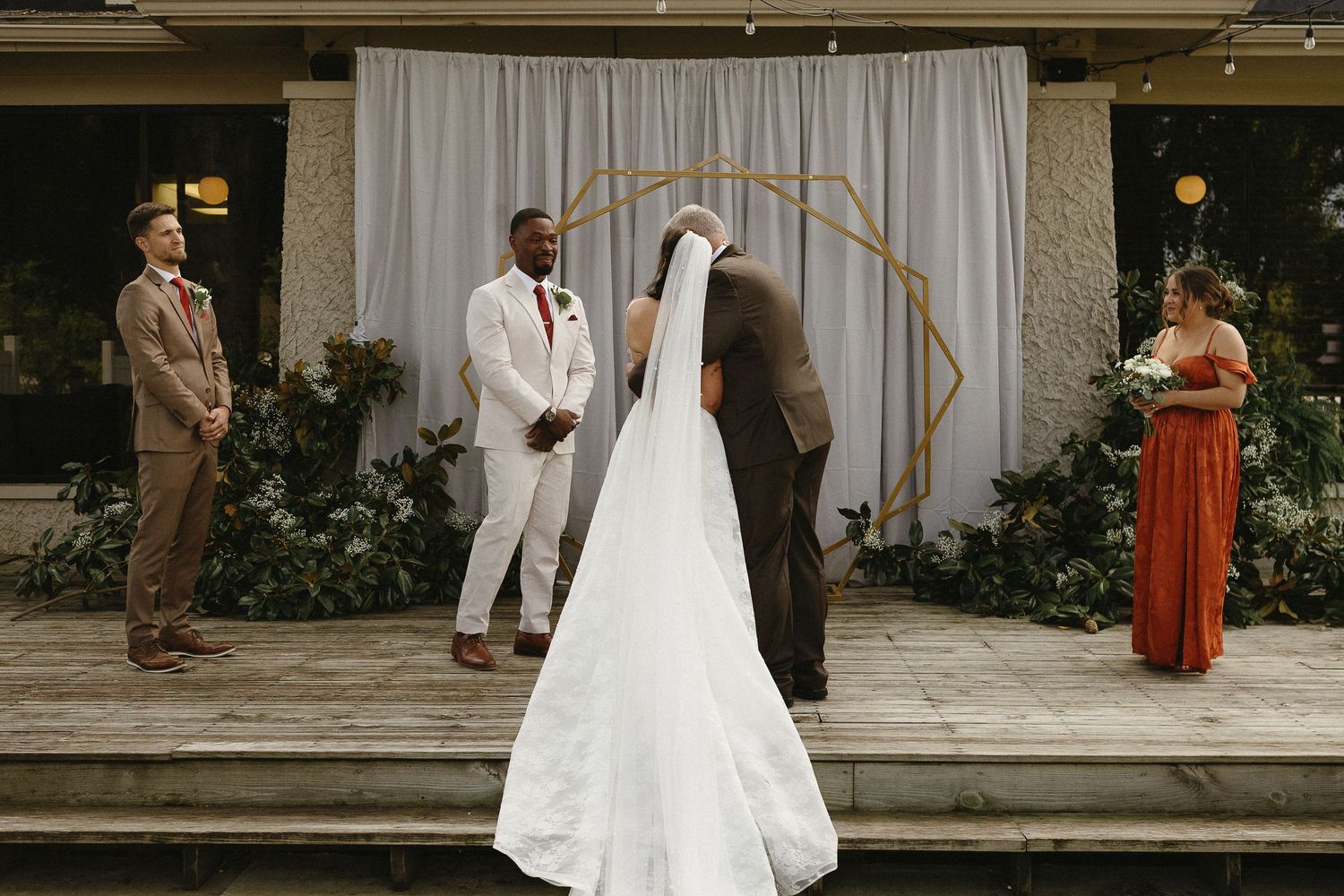 A row of wedding photos showing the back of a white wedding dress with flowing train and veil in an elegant venue.