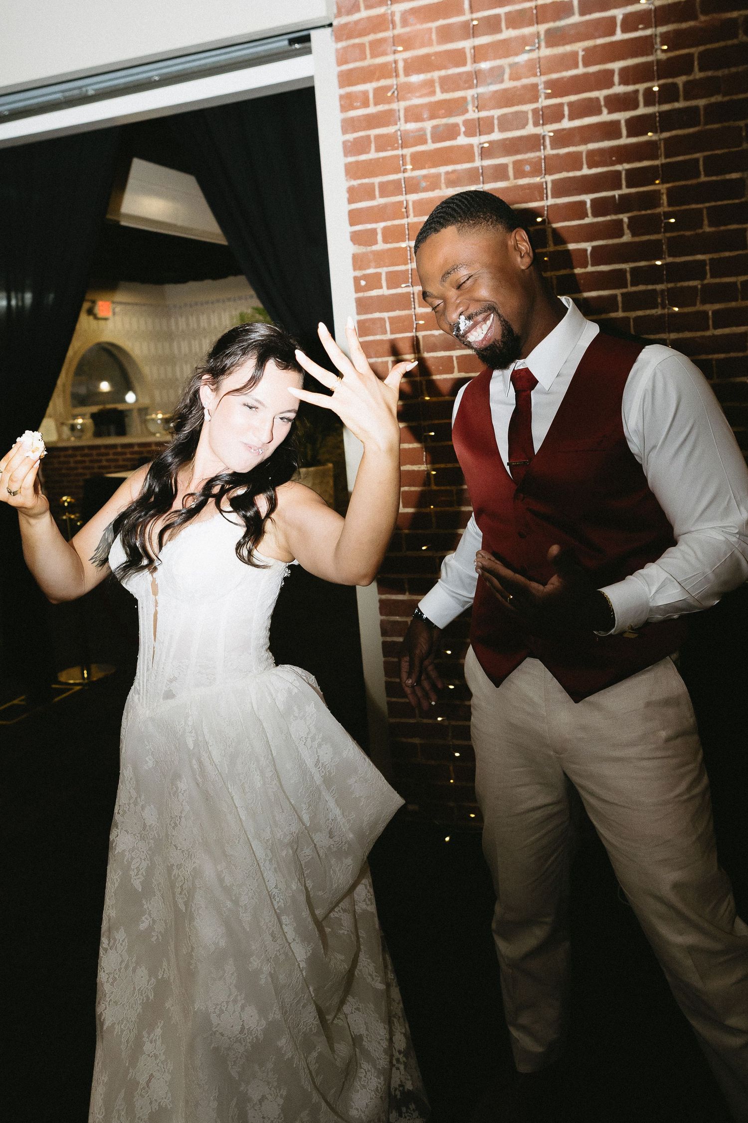 Wedding party members dancing and having fun against a brick wall background.