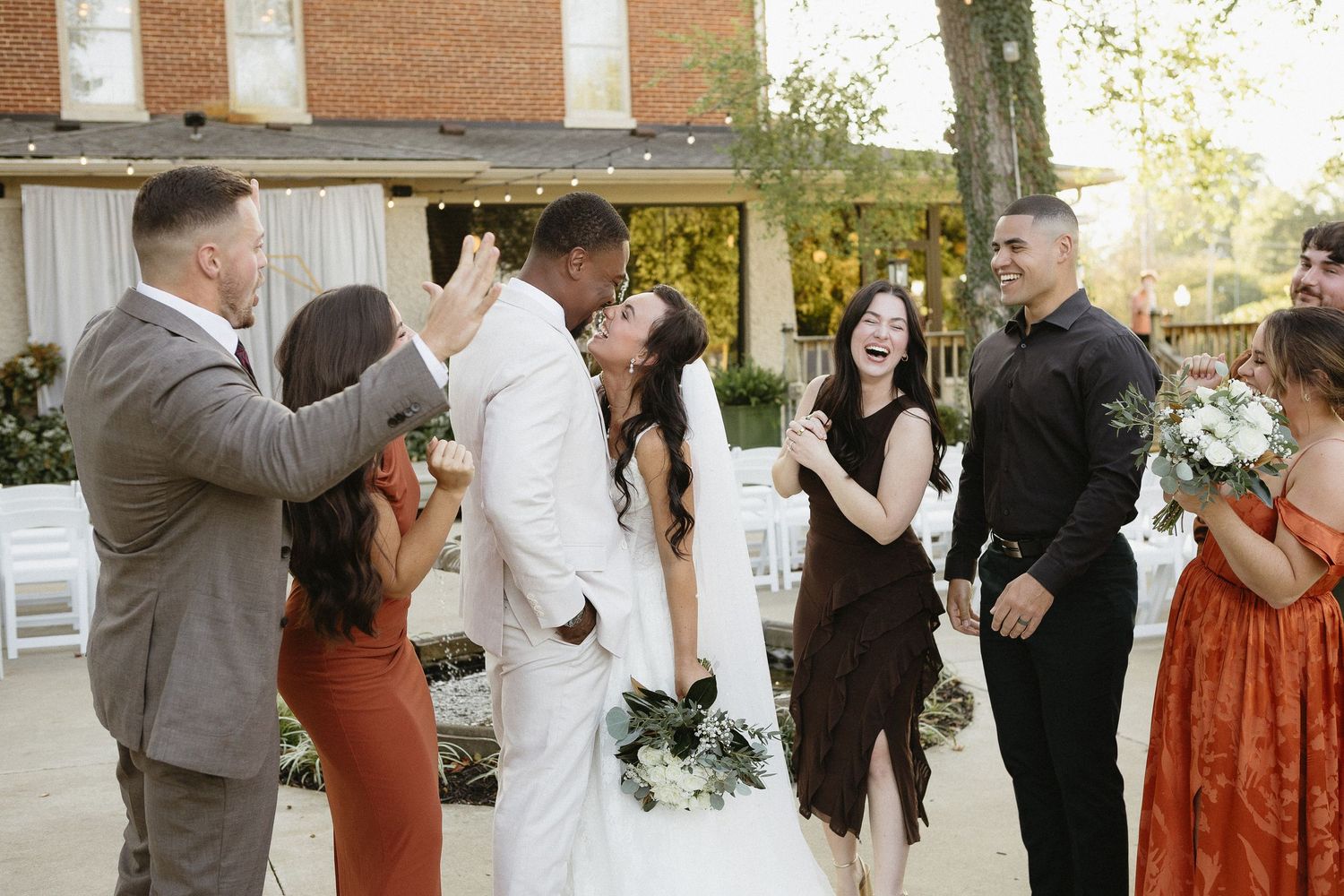 Wedding party and guests celebrating outside a brick building.