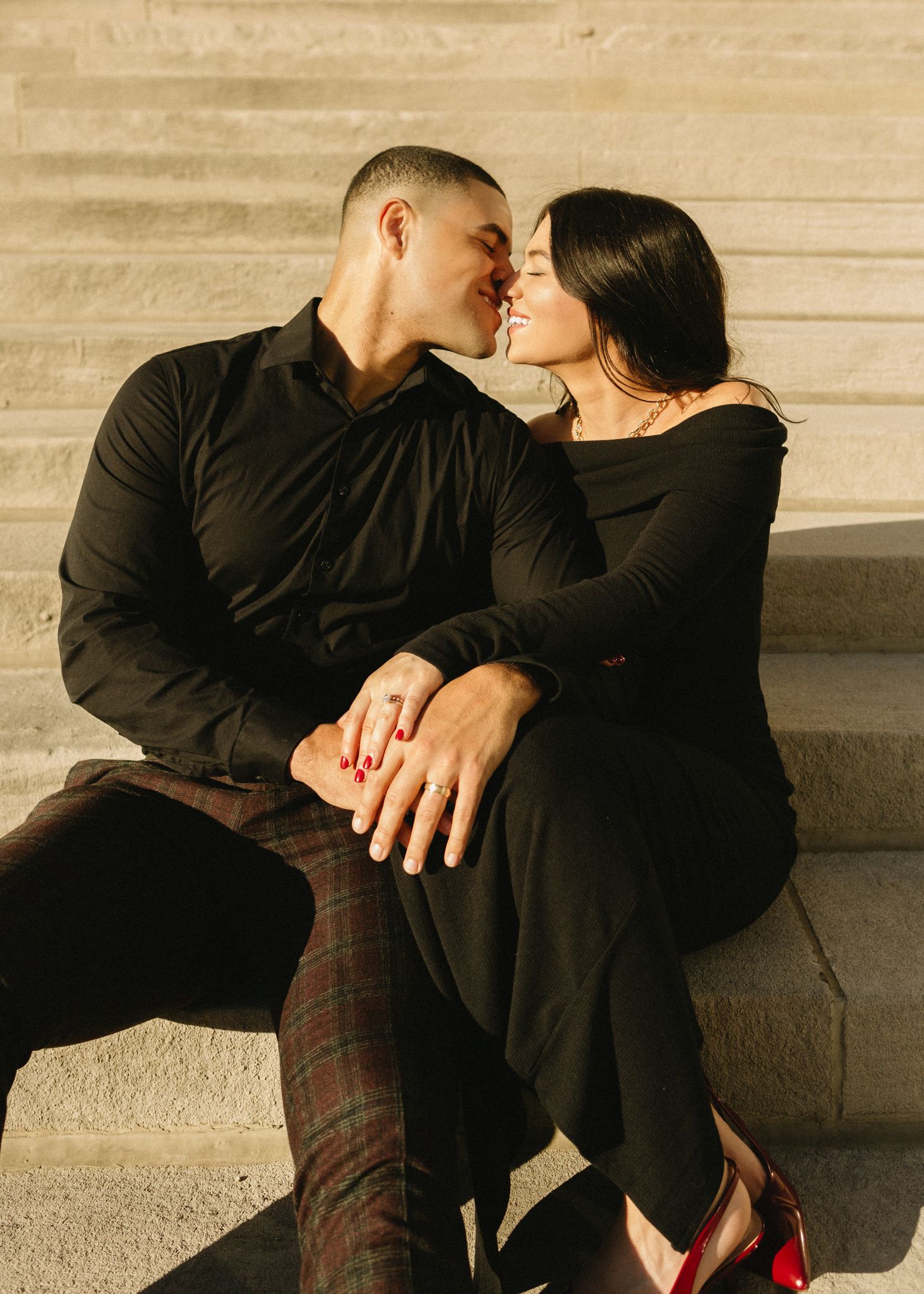 A romantic couple shares an intimate moment while sitting on stone steps at sunset.