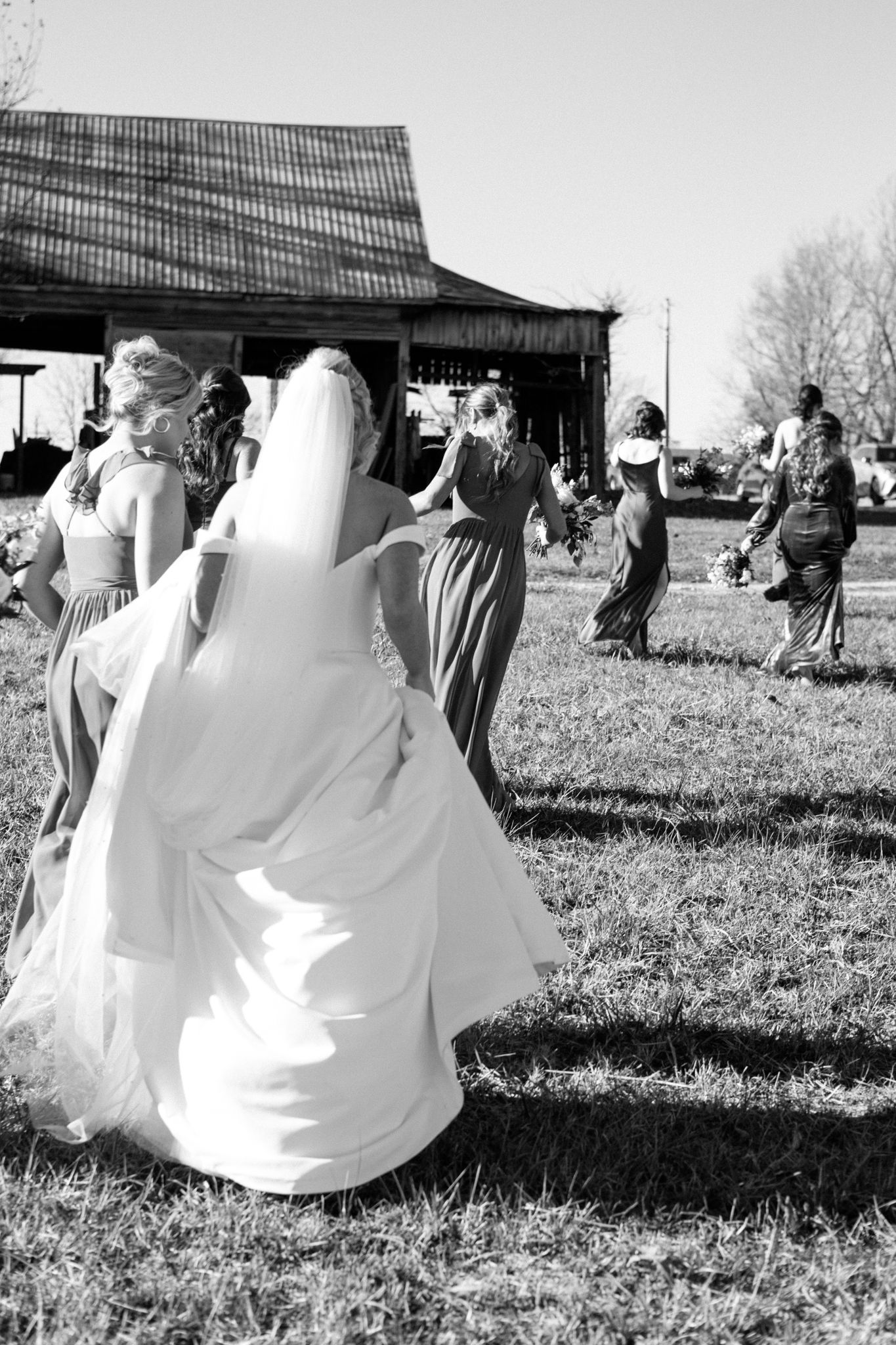 Smiling bride and bridesmaids in elegant wedding attire, posing together outdoors