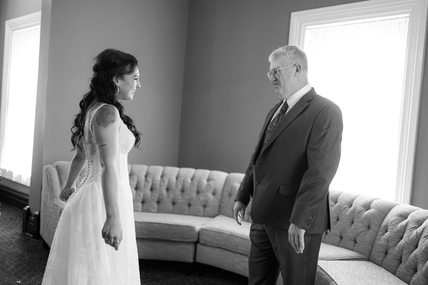 Black and white wedding photos showing intimate moments in a room with large windows.