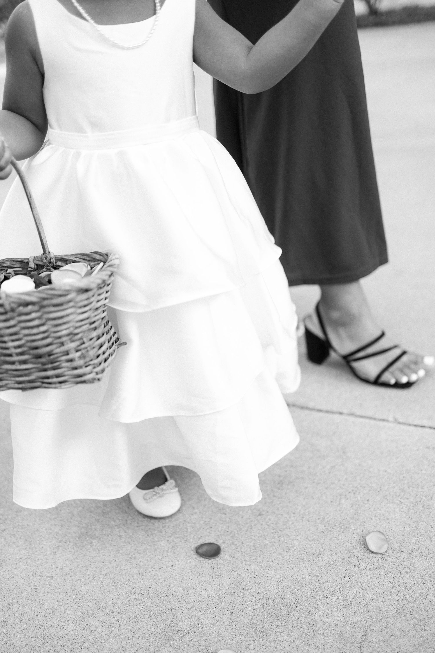 Black and white detail shot of wedding dress hemlines and shoes on carpet.