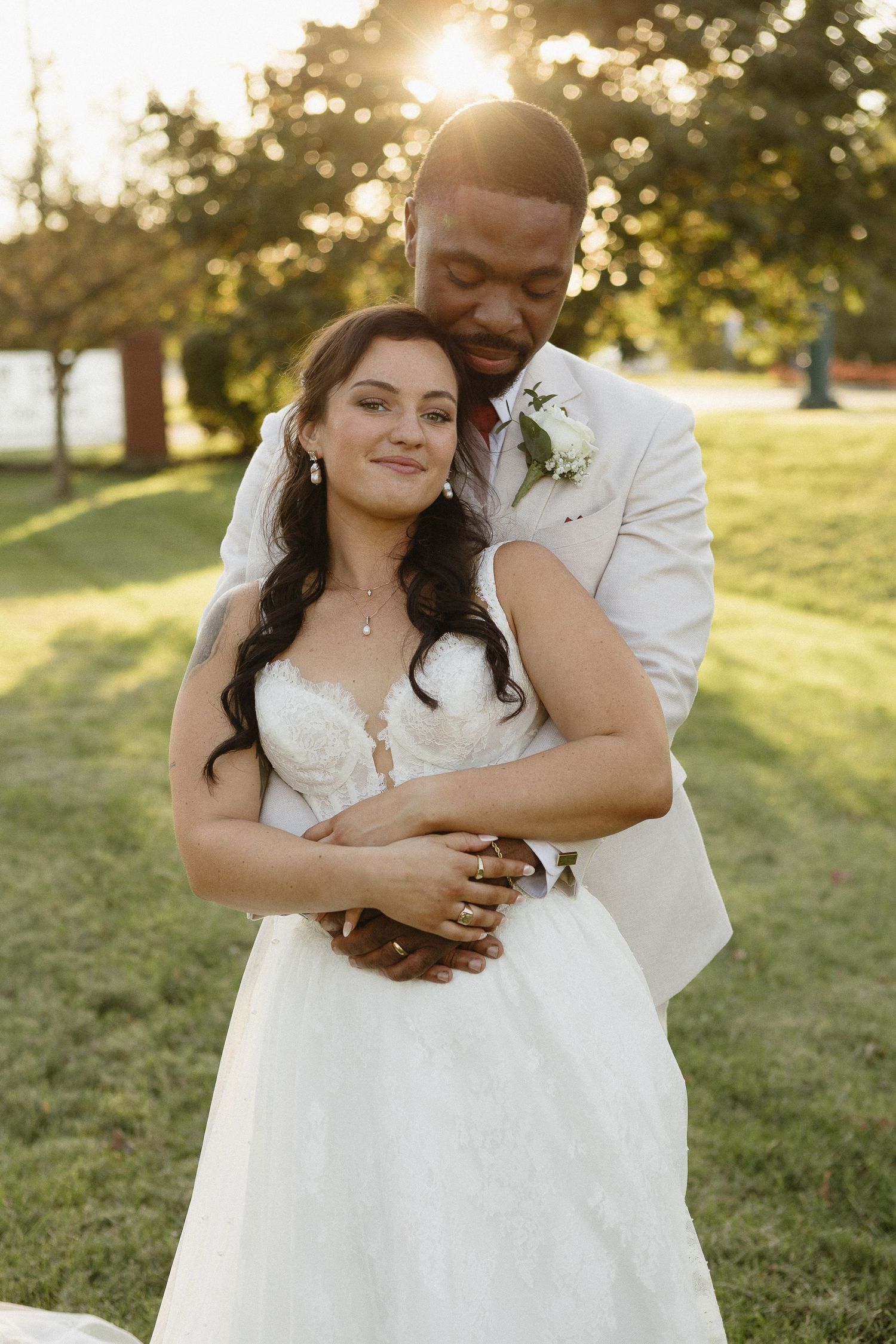 A romantic sunset wedding photoshoot showing tender embraces between a couple in a grassy field.