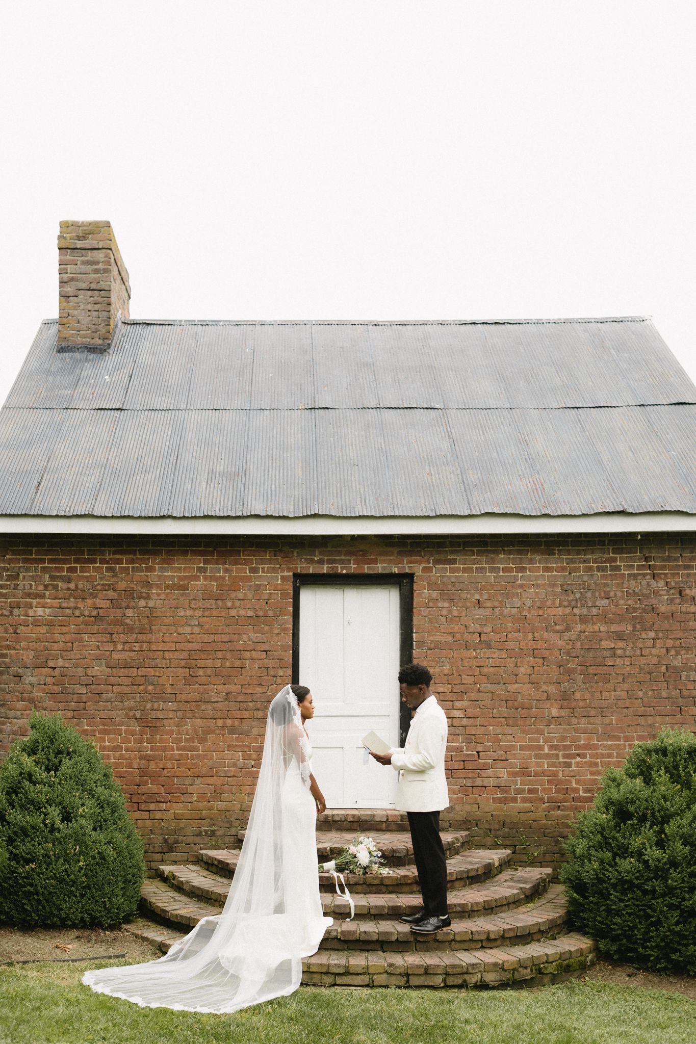 Wedding couple shares an intimate moment on curved brick steps outdoors.