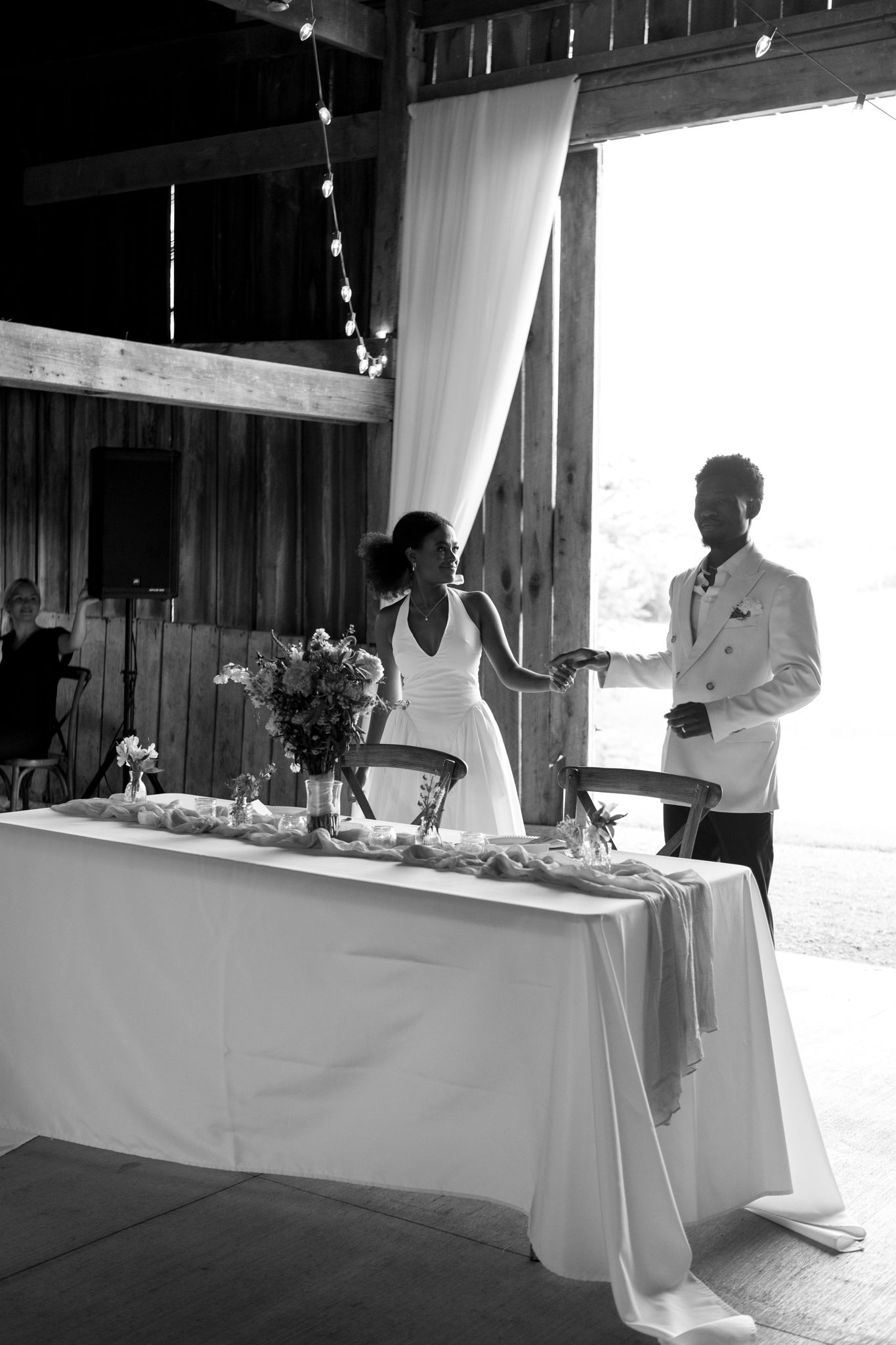 Black and white photo of elegant wedding reception setup in rustic barn venue.