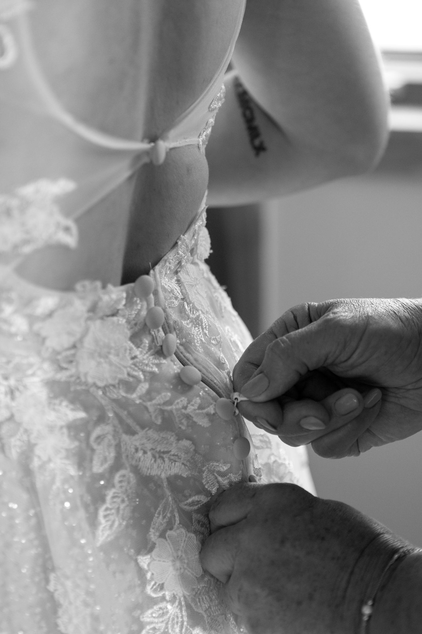 Close-up details of delicate lace being adjusted on a white wedding dress.