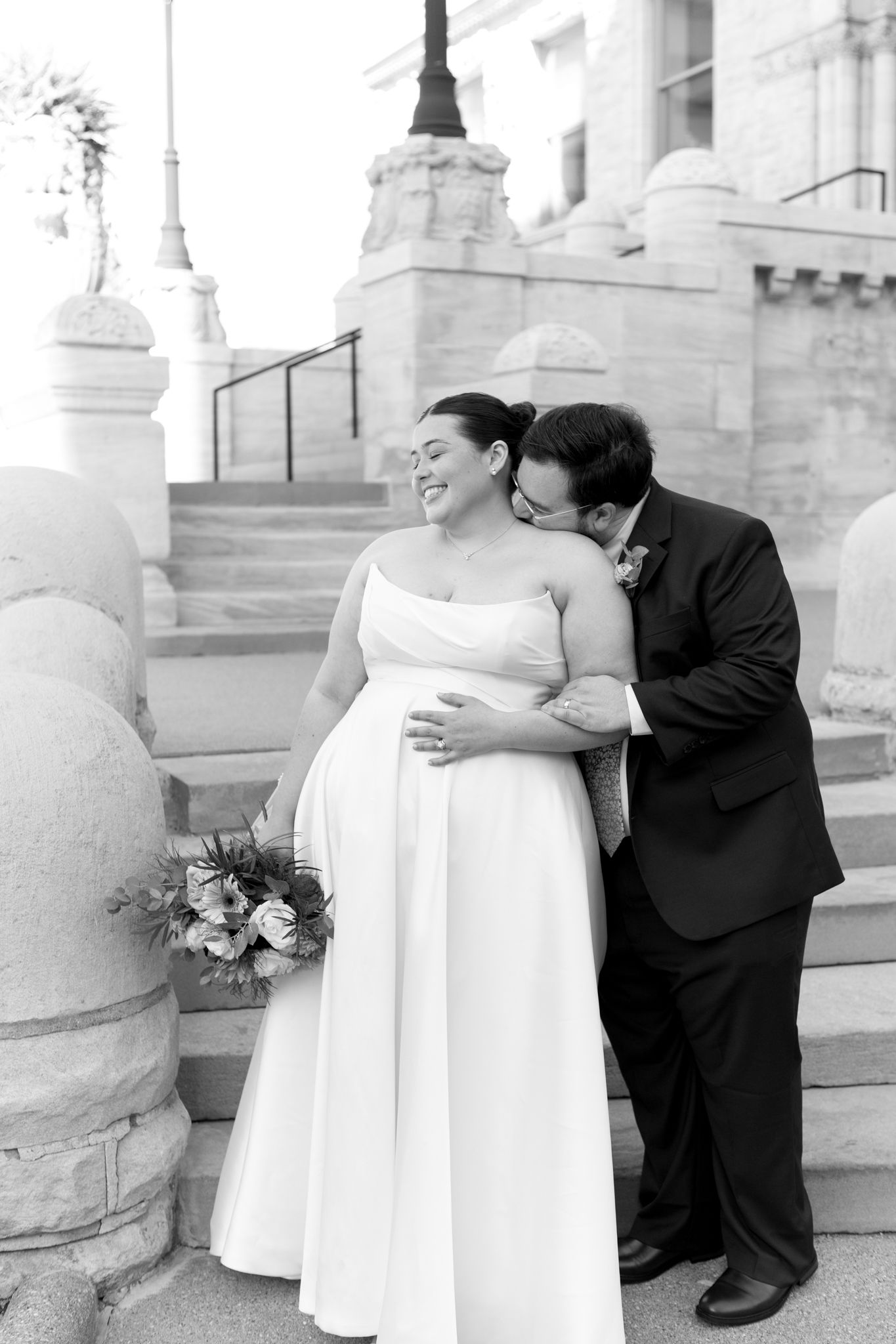 Black and white wedding photos of a couple embracing on marble steps of a historic building.