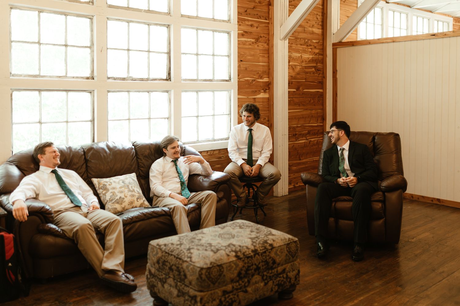 A group of men relaxes on a couch, enjoying each other's company in a cozy room setting