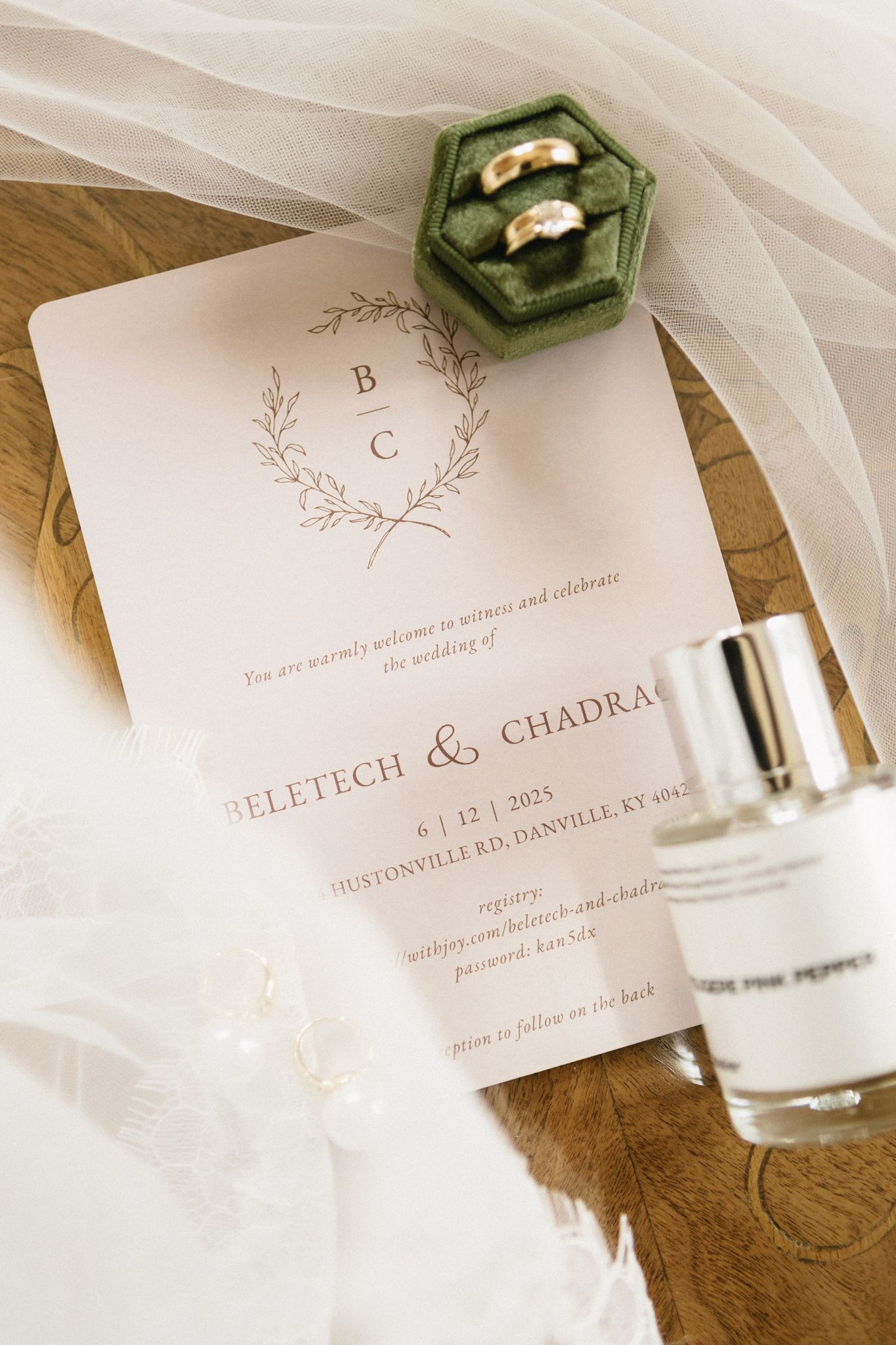 Elegant wedding invitation details with monogram letterpress and green glass vials on a soft white background.