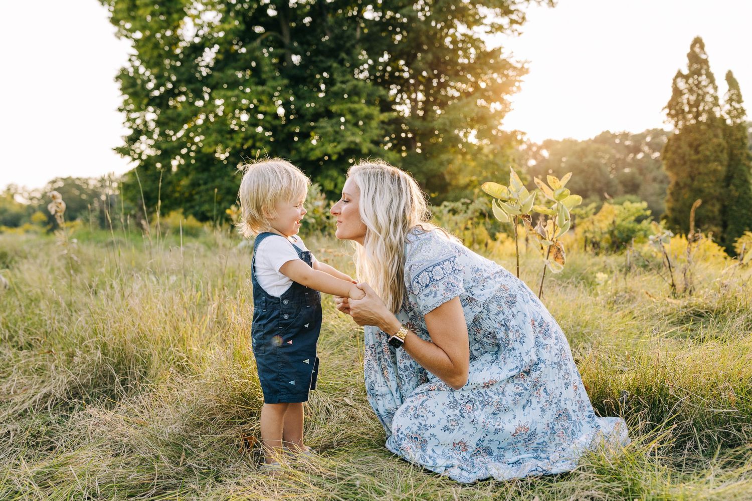 Mother and son in a grassy field at sunset.