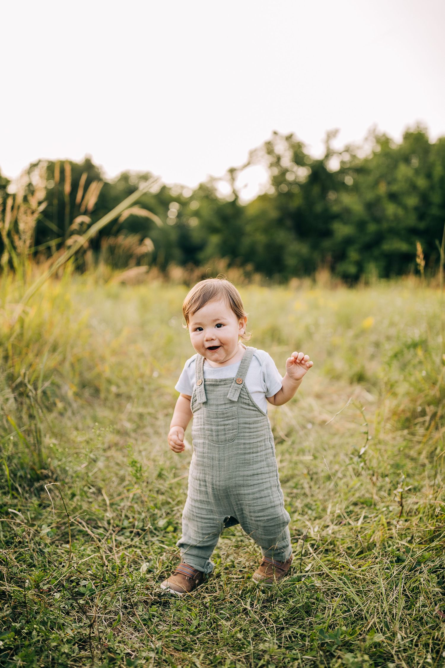 Young boy in a grassy field with wildflowers during the summertime.