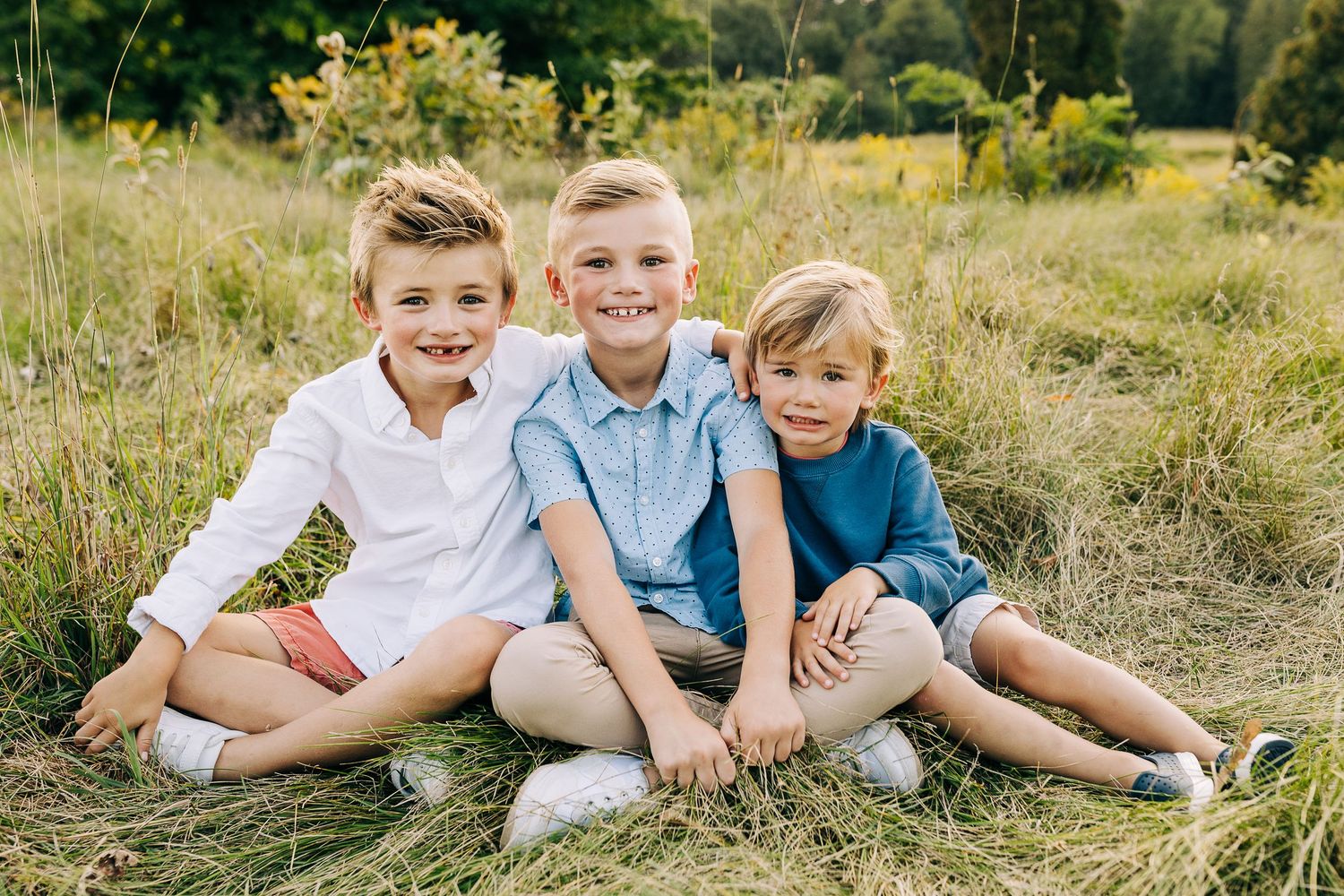 Boys sitting in a grassy field.
