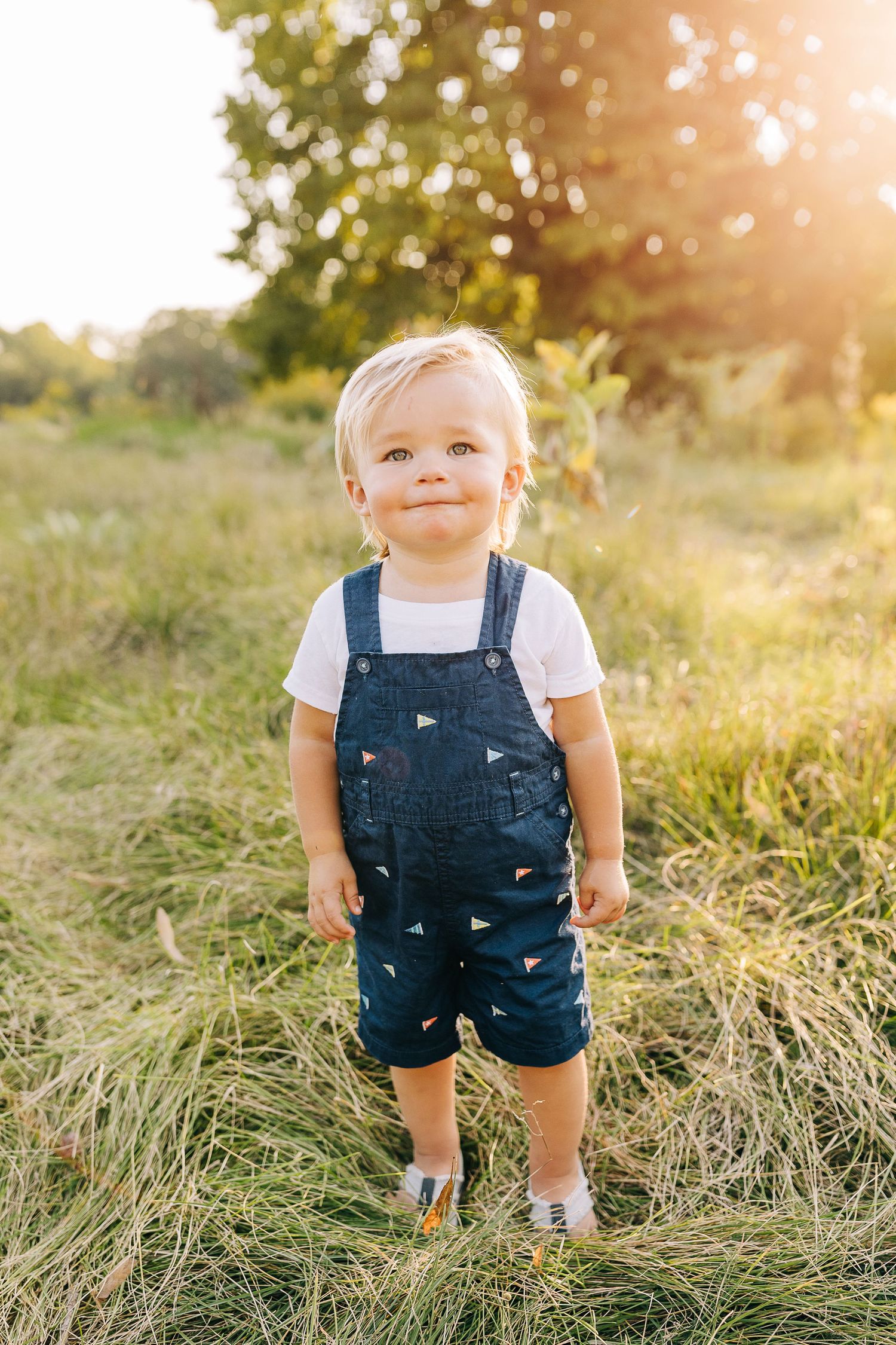 Young boy in a grassy field at sunset.