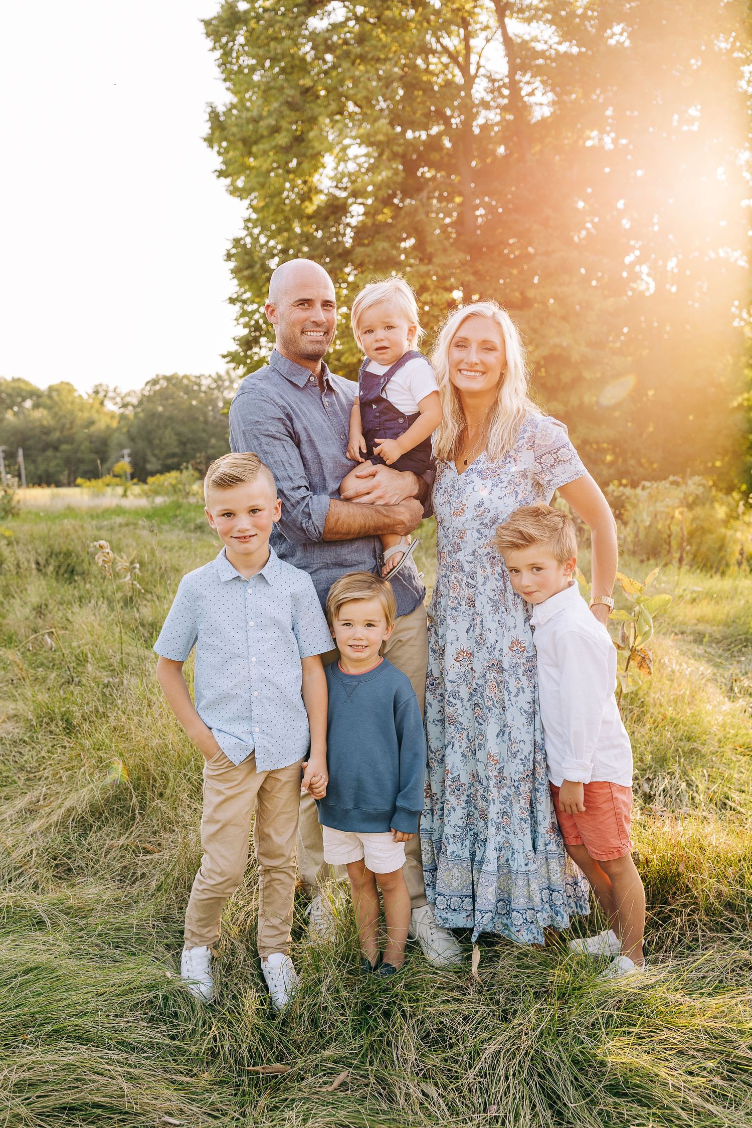 Family portrait in a grassy field at sunset.