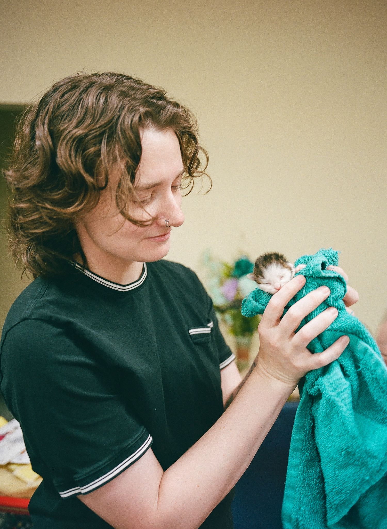 Fine art portrait of a white woman with curly brown hair holding a newborn kitten, captured in medium format film photography style.