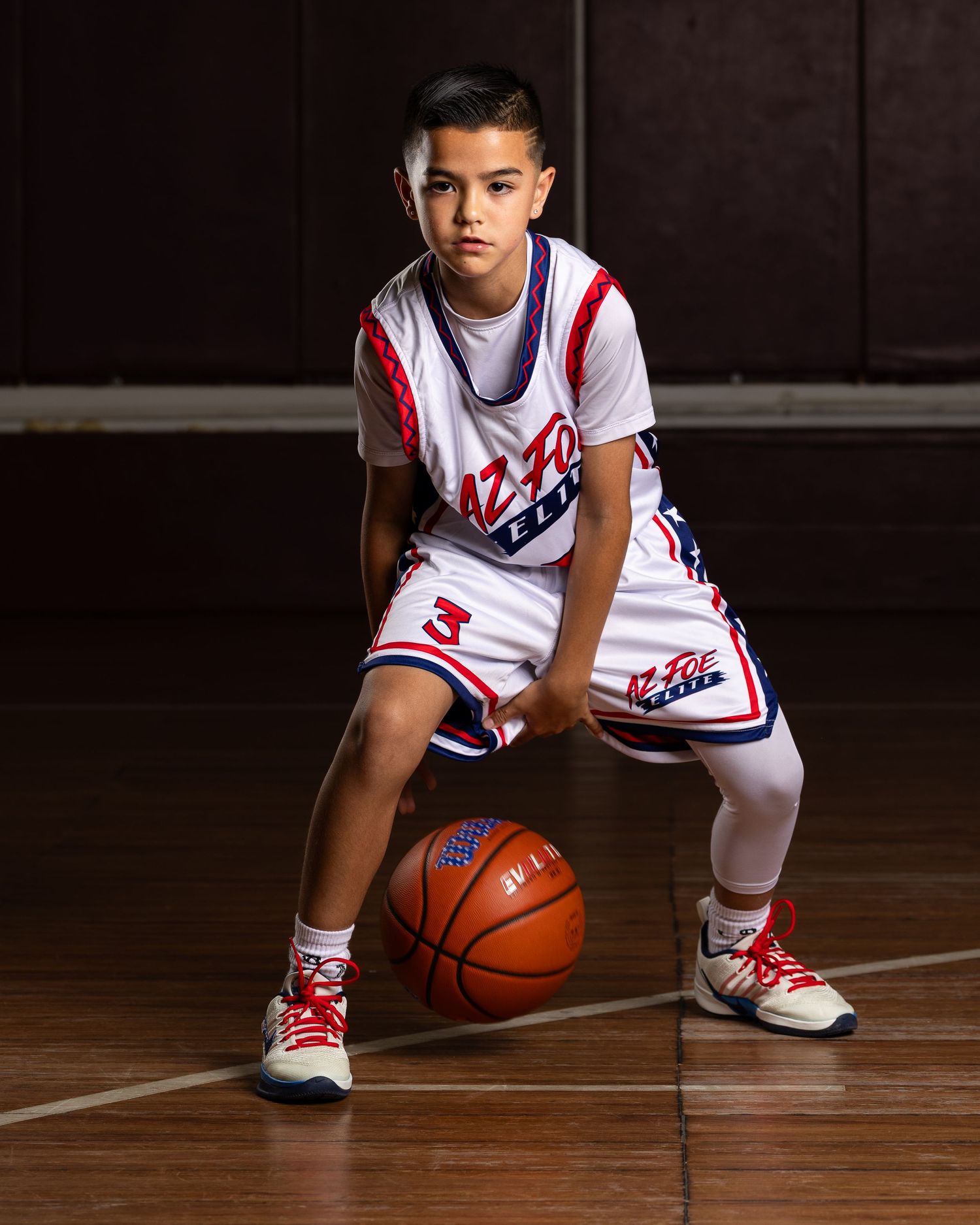 Young boy #3 in AZ Foe Elite white basketball uniform poses with ball on court in professional portrait.