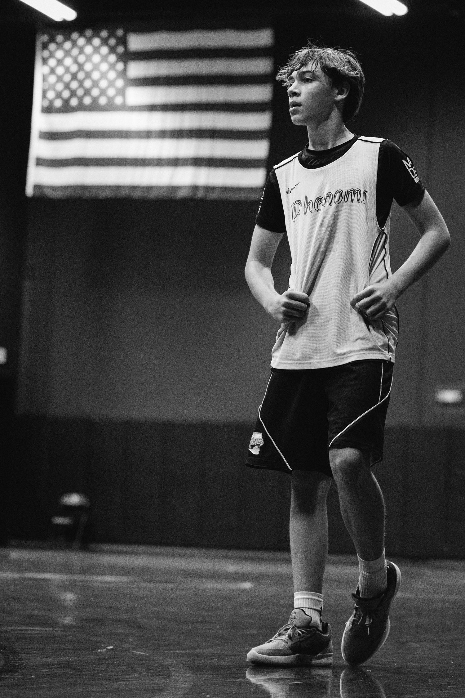 Black and white photo of young basketball player in Phenoms jersey holding water bottle.