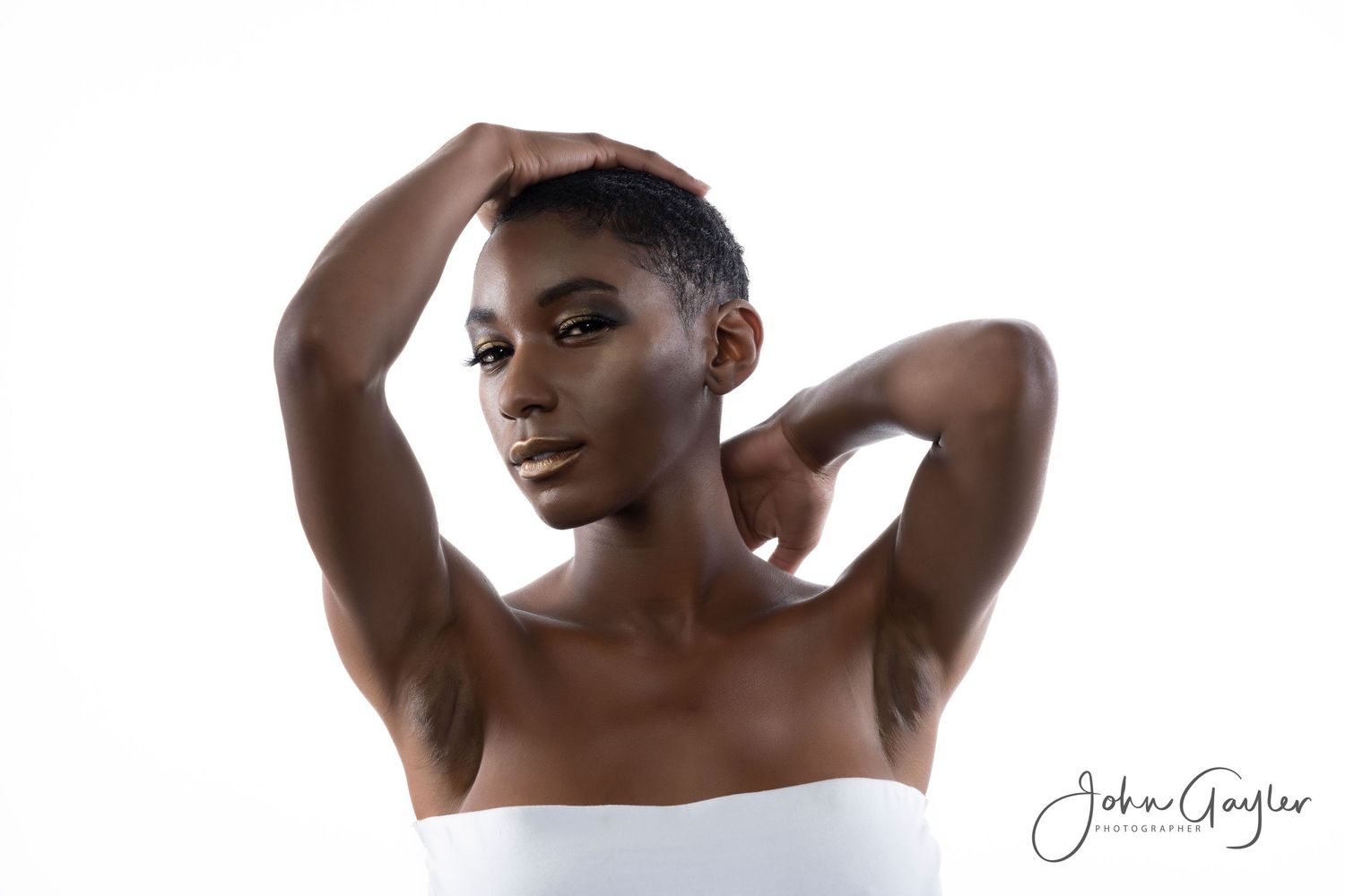 Artistic portrait of a black model in a white top posing elegantly against a white background.
