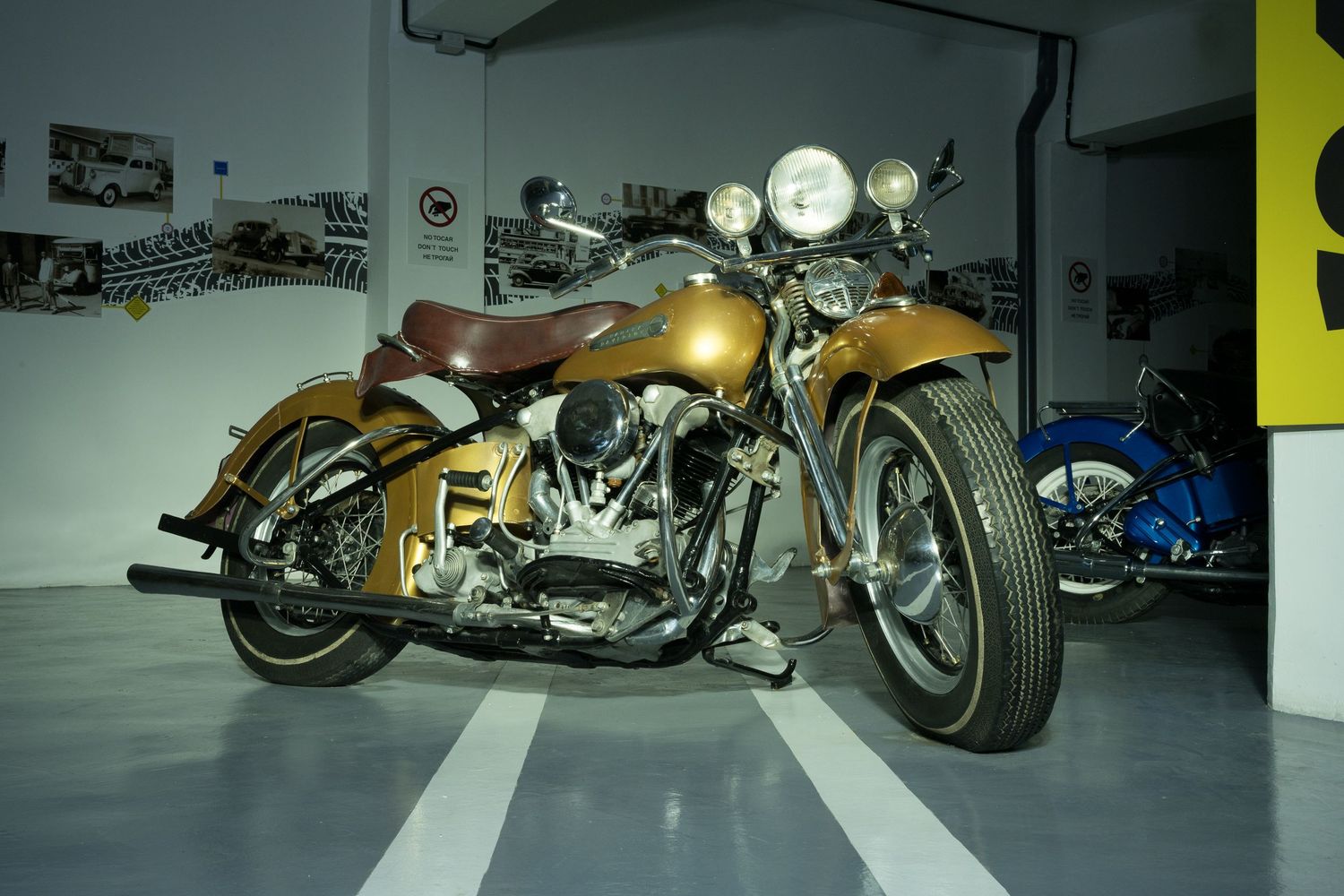 A  classic 1942 Harley Davidson Knucklehead motorcycle with gold paint in a museum setting by john Gayler Photography.