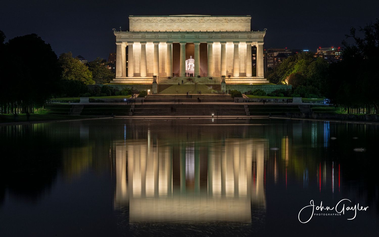 The Lincoln Memorial illuminated at night reflects beautifully in the still waters of the reflecting pool in Washington DC.