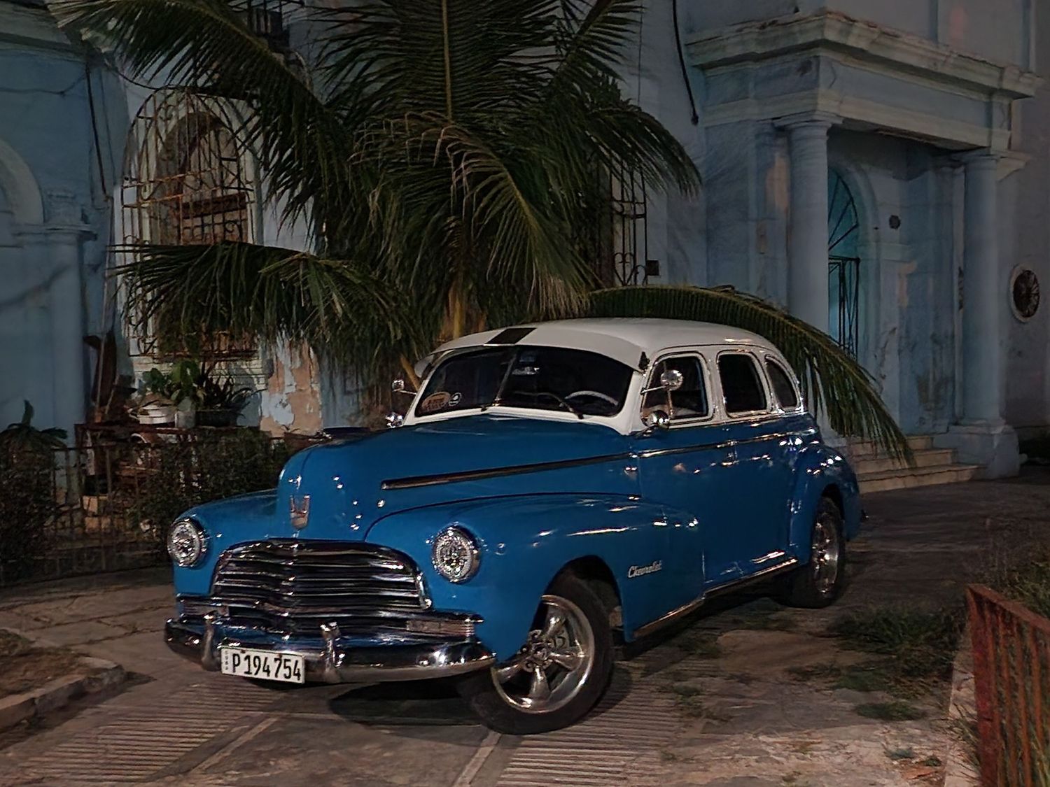 Cell phone image of a 1946 Chevrolet Fleetmaster with blue and white paint outside a hacienda in Old Havana Cub