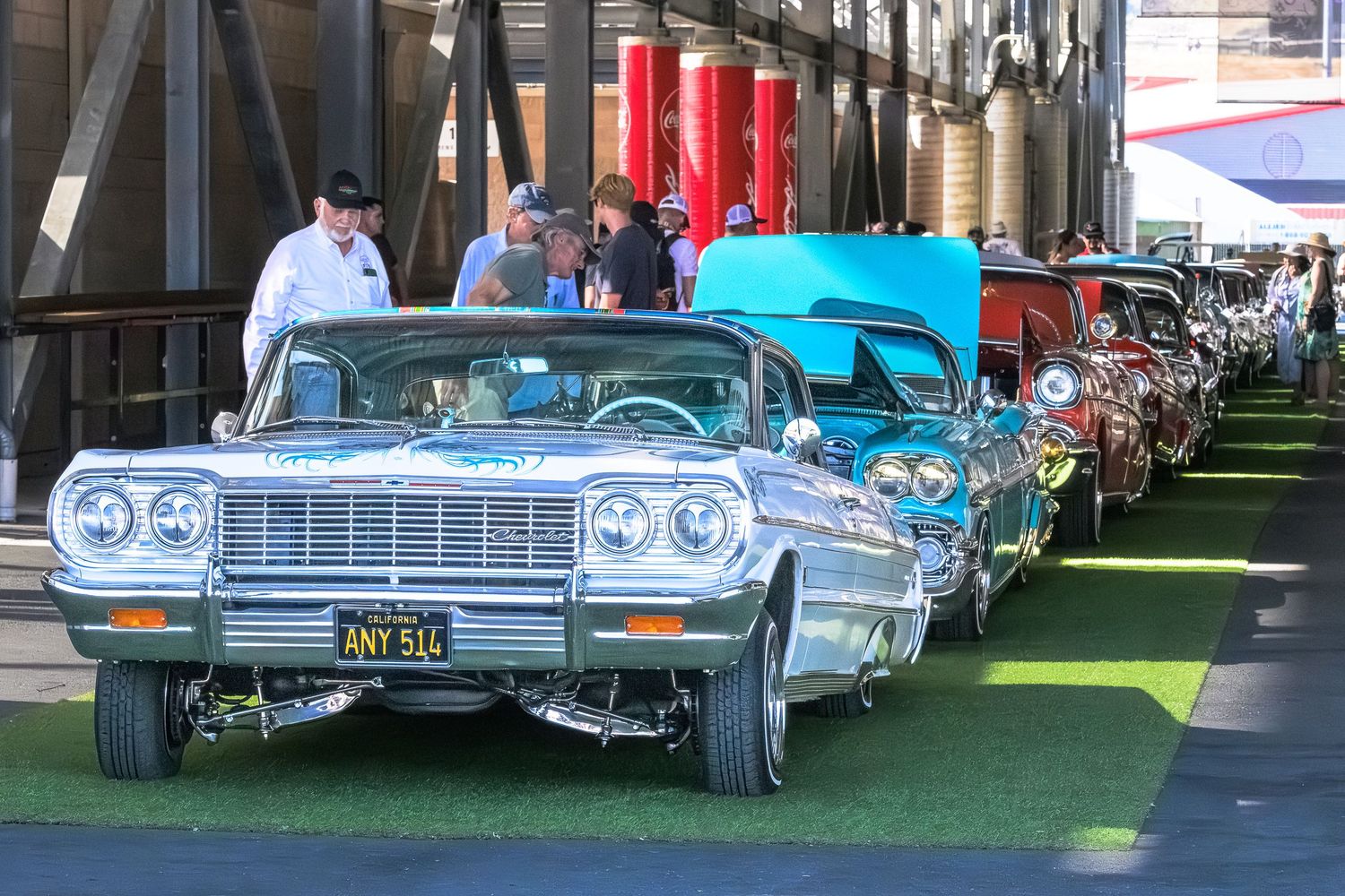 Classic vintage cars lined up in a row at an outdoor car show displaying pristine chrome and paint finishes.