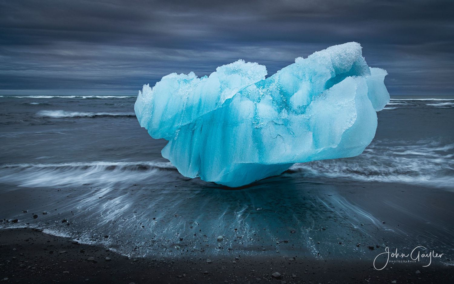 A lone iceberg calved from a glacier sits stranded on the beach by the outgoing tide at Jökulsarlon in Iceland.
