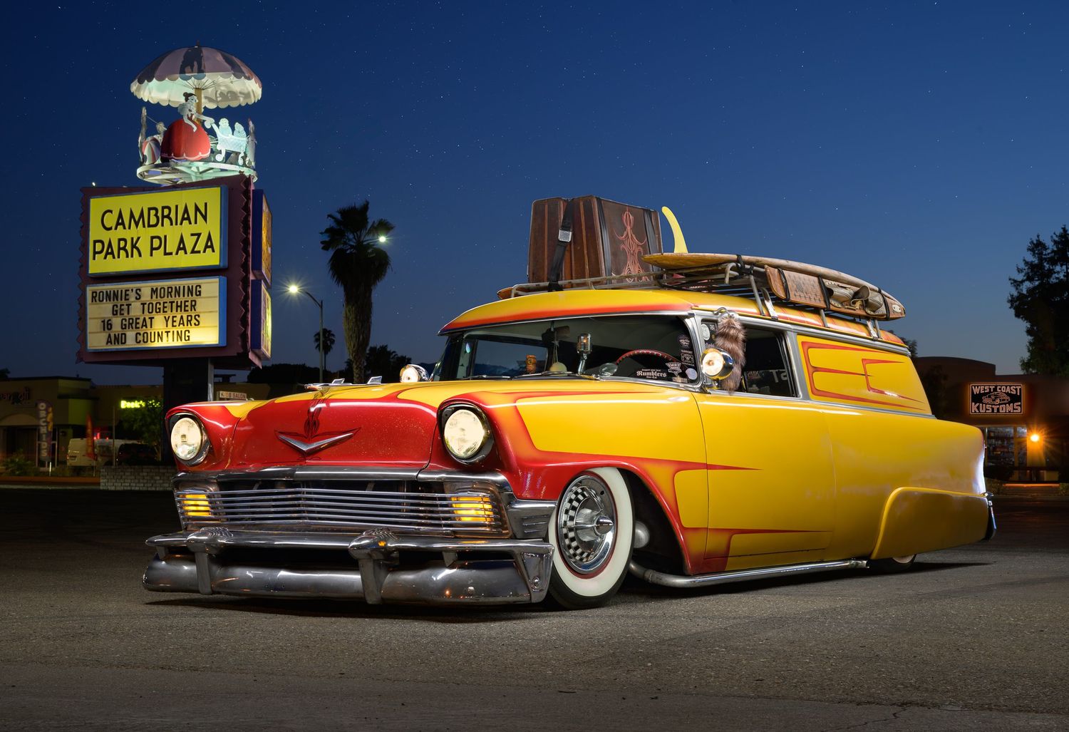 John Gayler Light Painting of a 1963 Chrysler Delivery wagon in yellow paint with red accents, surfboard and suitcase at Cambrian Plaza