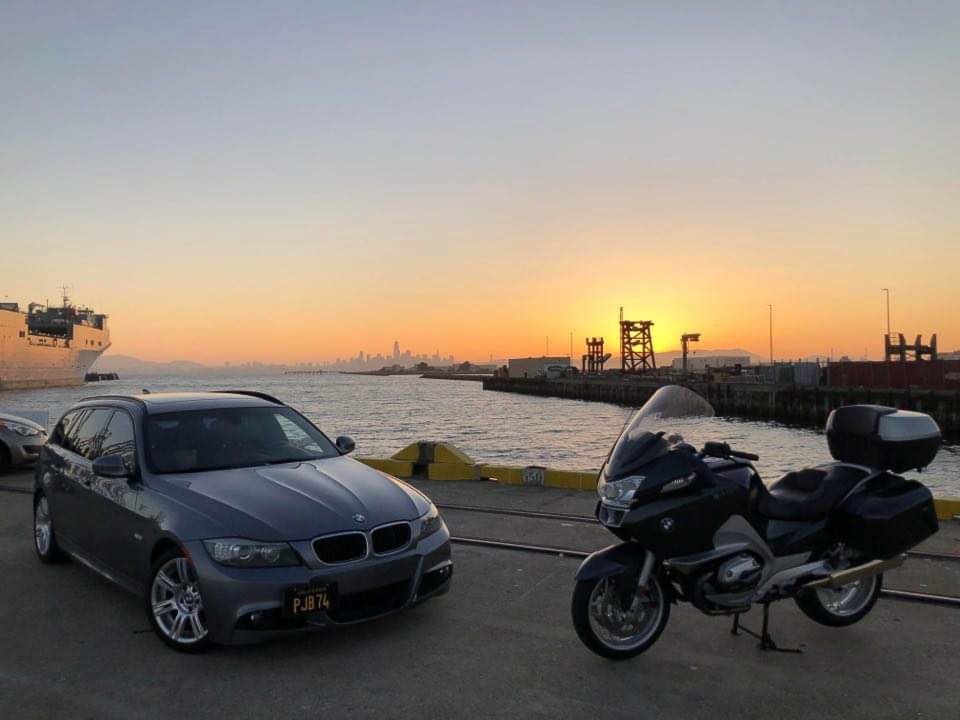 Cell phone photograph of BMW wagon and BMW touring bike positioned against San Francisco skyline for a John Gayler Light Painting portrait