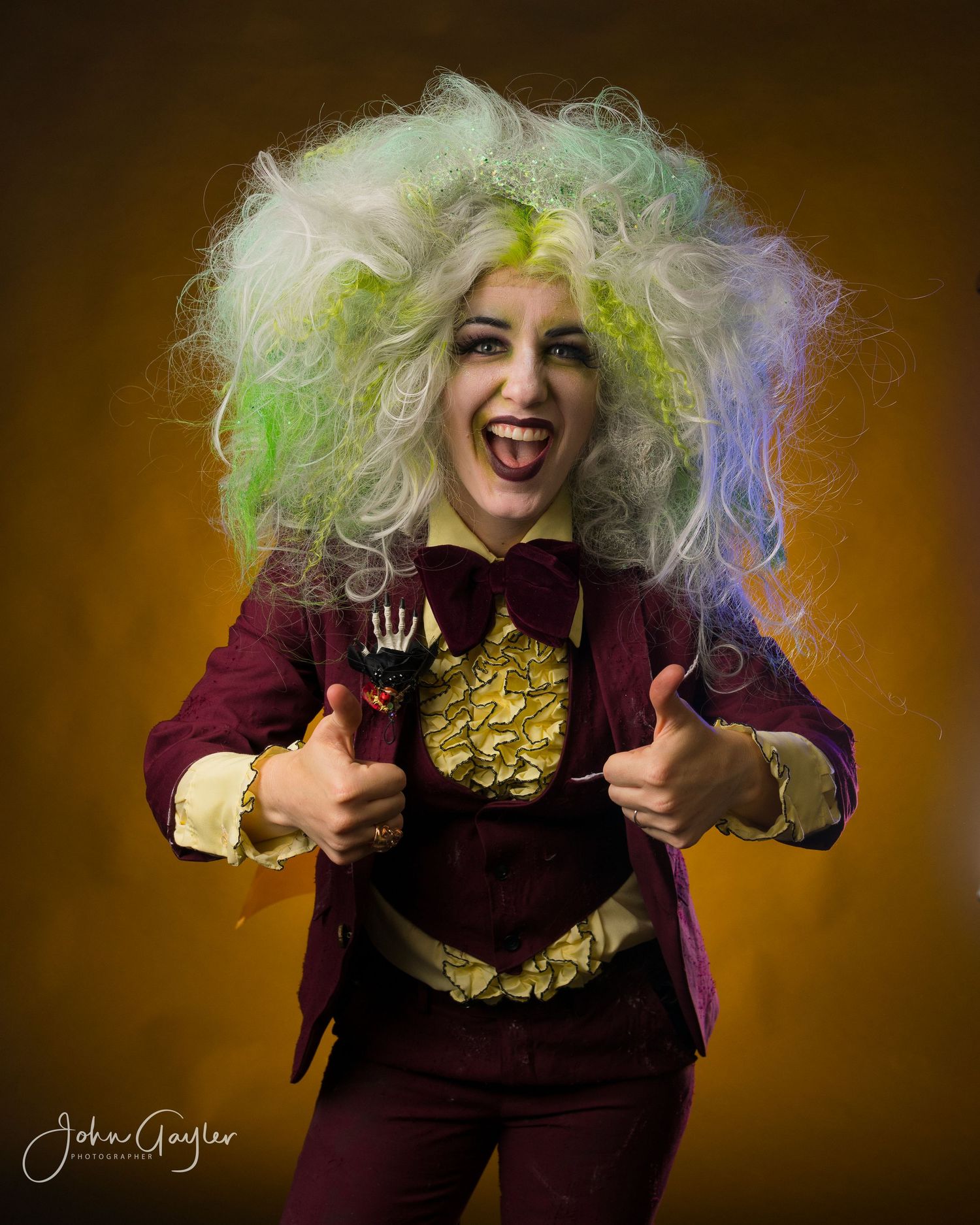 A Beetlejuice figure with wild neon green and white curly hair poses expressively in a burgundy outfit against a dark background.
