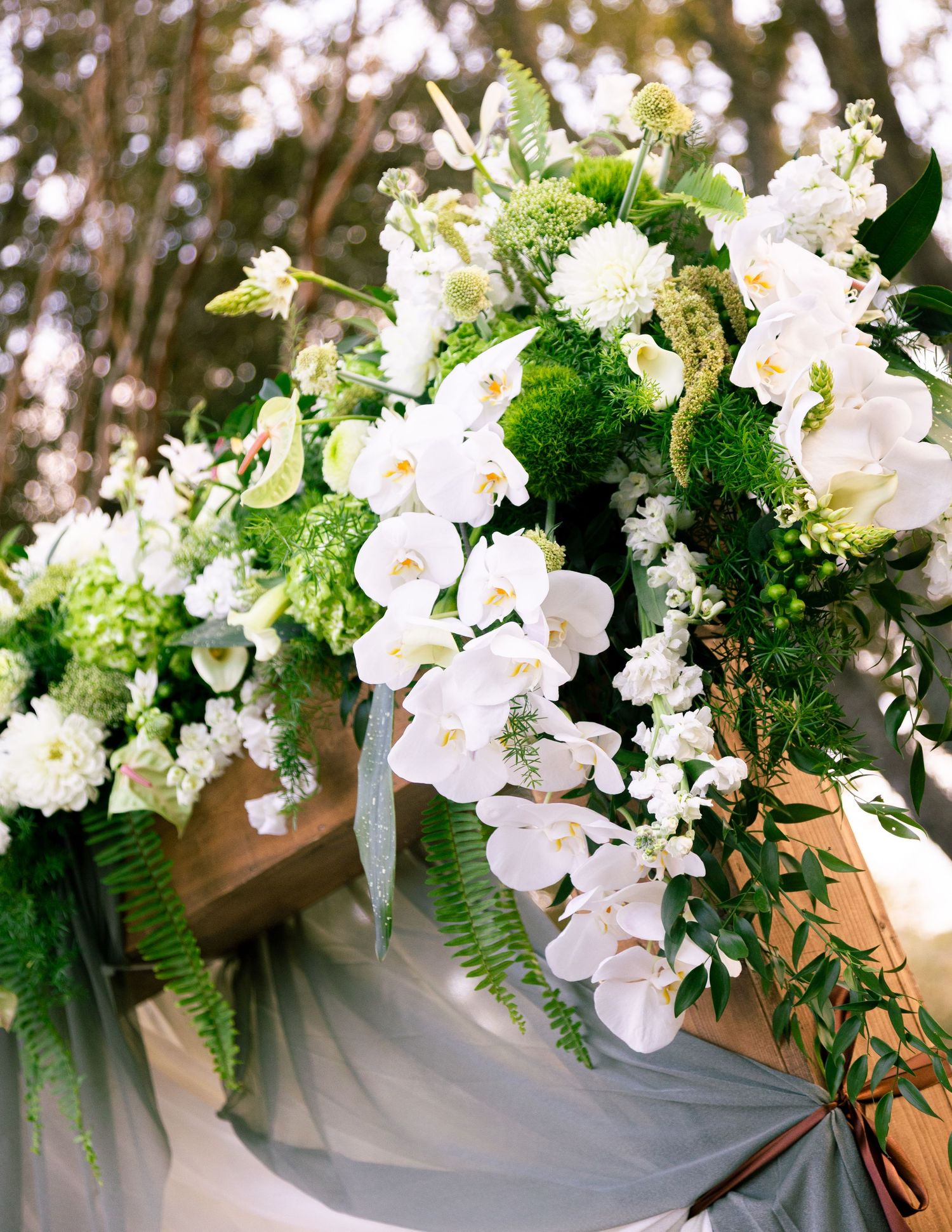 Elegant white floral wedding ceremony arrangements with orchids and greenery.