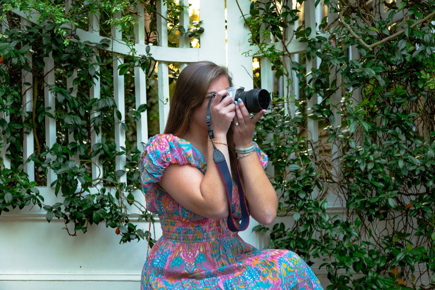 Photographer capturing images through a professional camera lens in a garden setting.