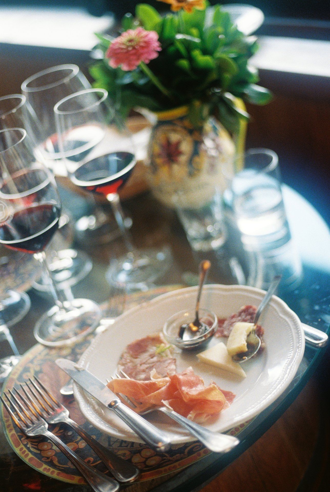 Elegant table setting with wine glasses, prosciutto appetizers and floral centerpiece.