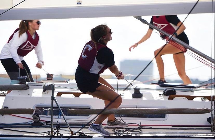 Crew members working on deck of racing sailboat during competition.