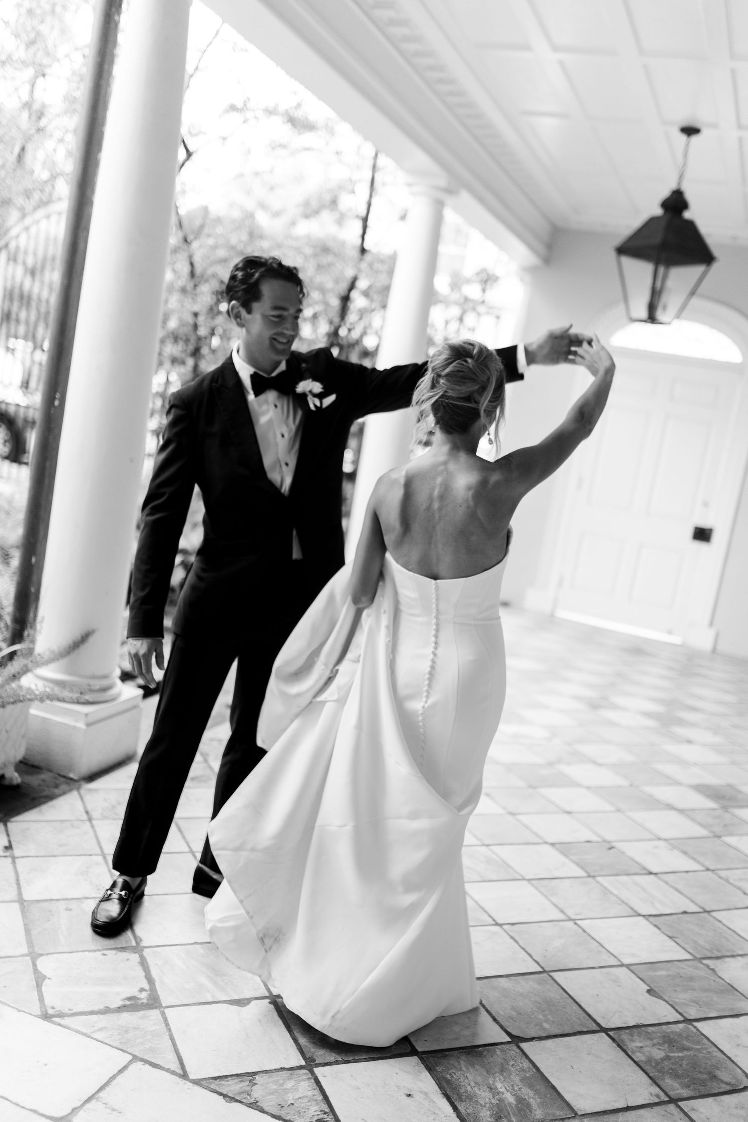 A couple dances together on an elegant porch with white columns.