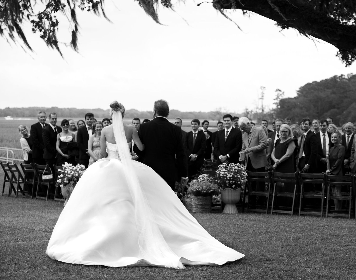 Black and white panorama of an outdoor wedding ceremony setup with guests seated on a lawn.