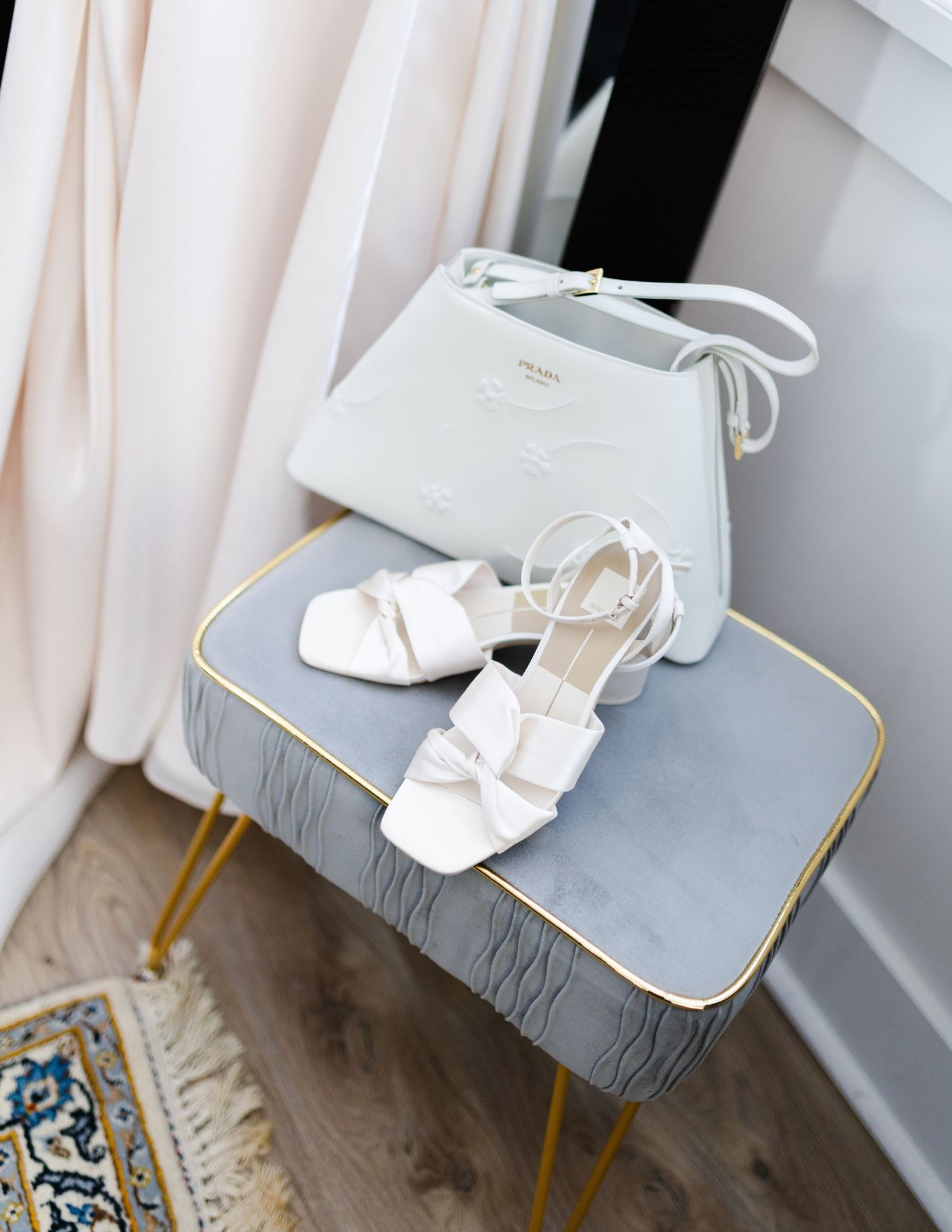 White bridal shoes displayed on gray upholstered chairs with gold legs.