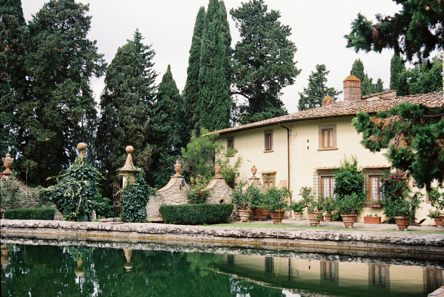 Panoramic view of an Italian villa garden with cypress trees and stone balustrades.