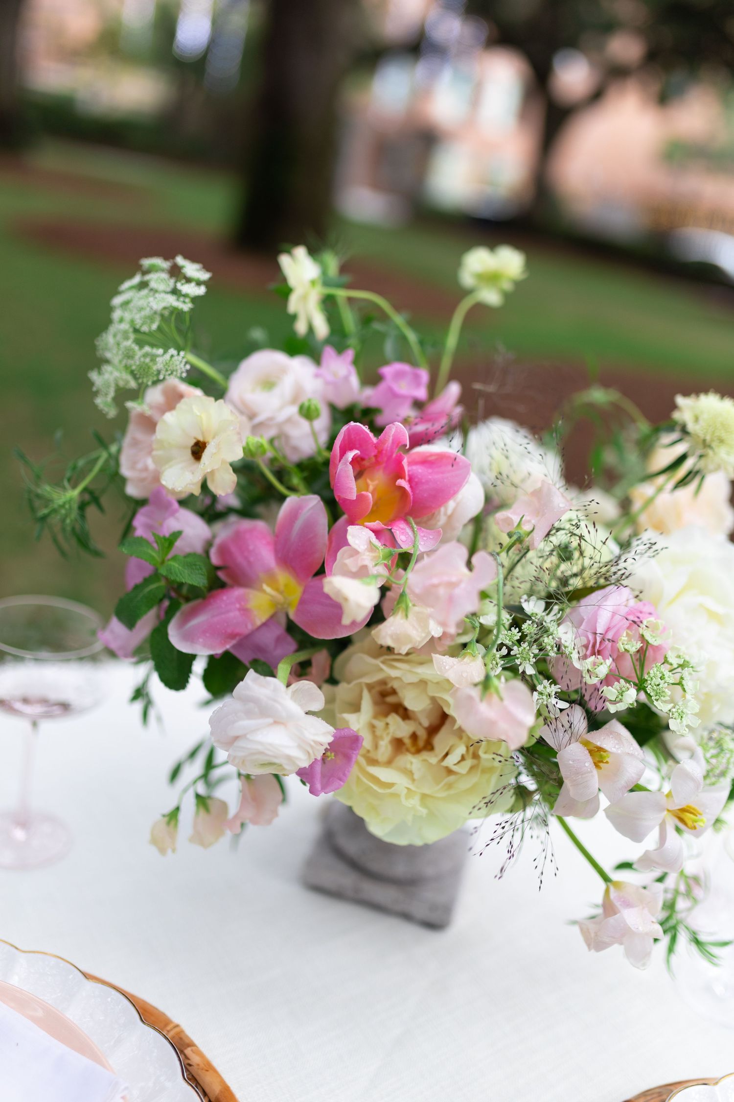 Delicate floral centerpieces with pink and white flowers arranged on white tablecloths.