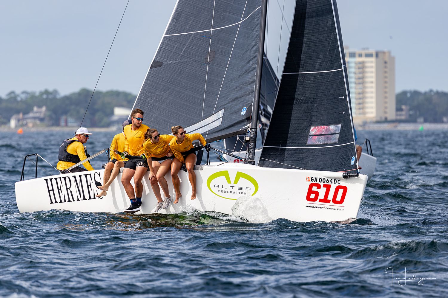 Sailboats racing across blue waters with crews leaning out to balance during a competitive regatta.