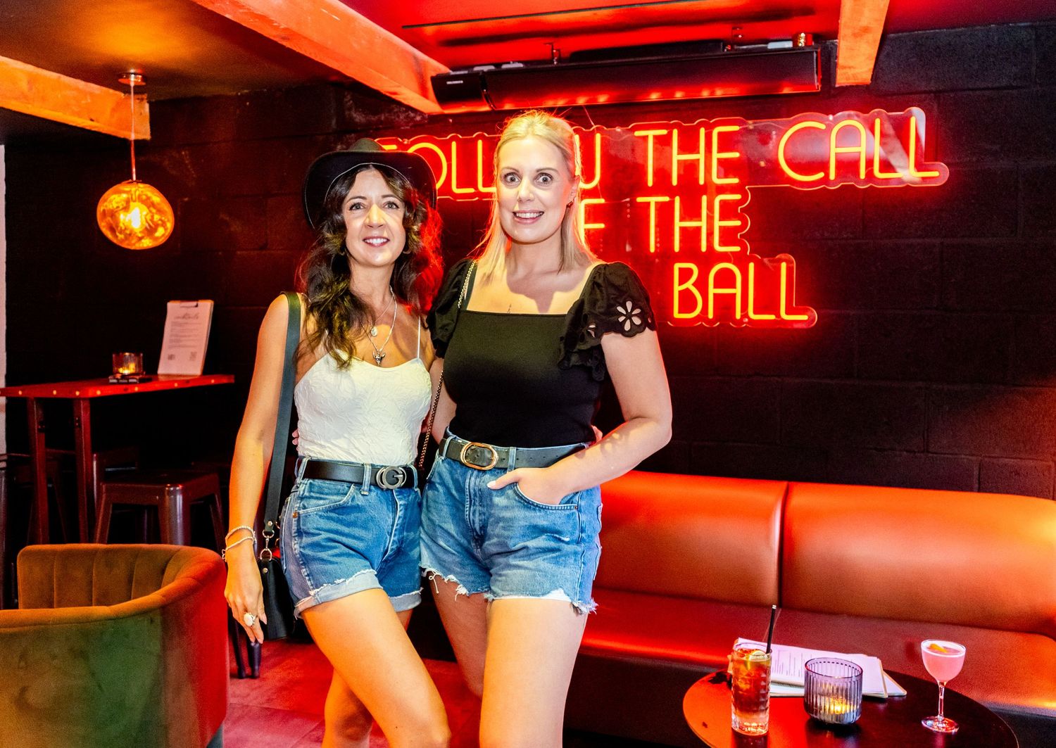 Bar scene with red neon signage and patrons enjoying the nightlife.