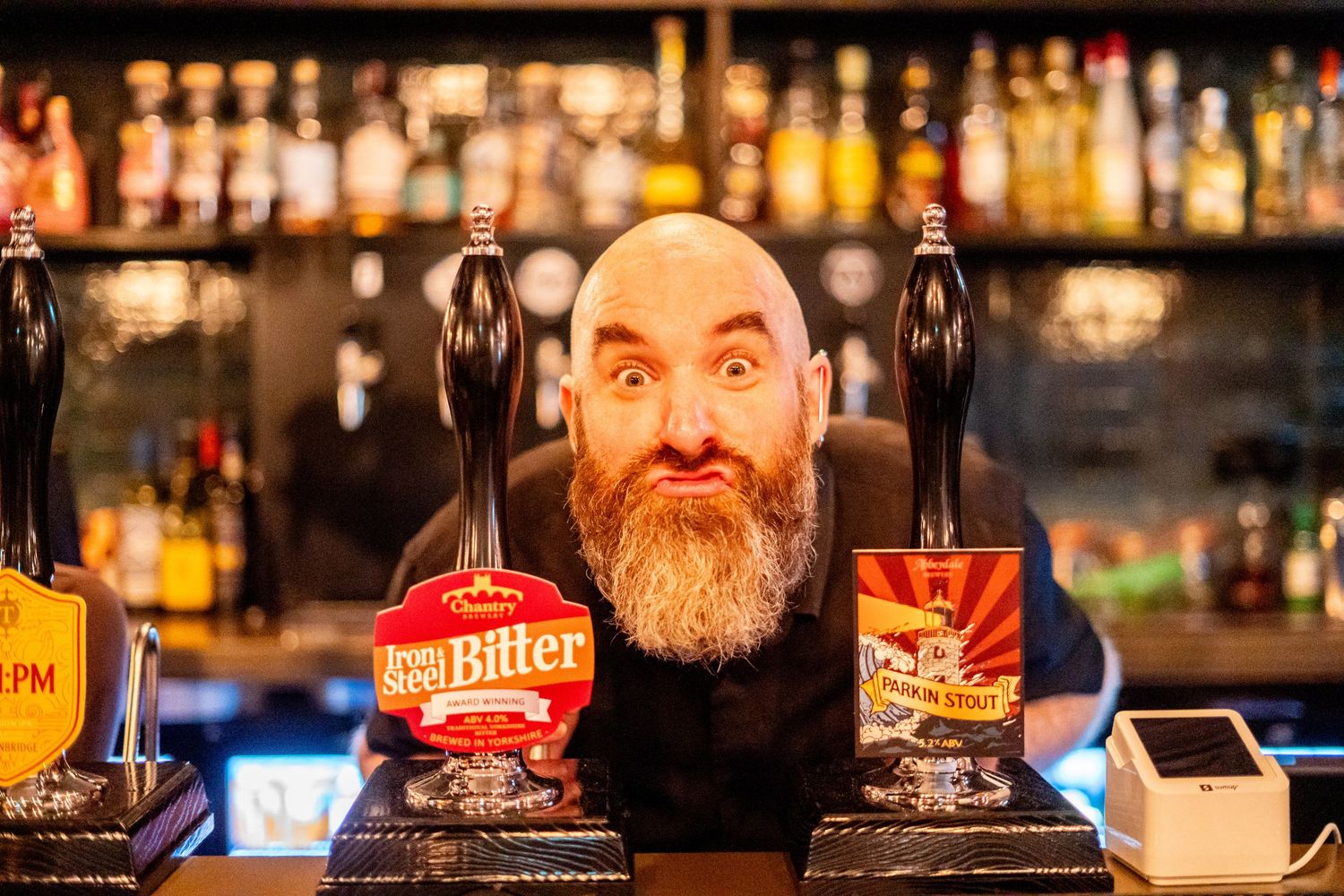 Beer taps at bar counter with branded merchandise display.