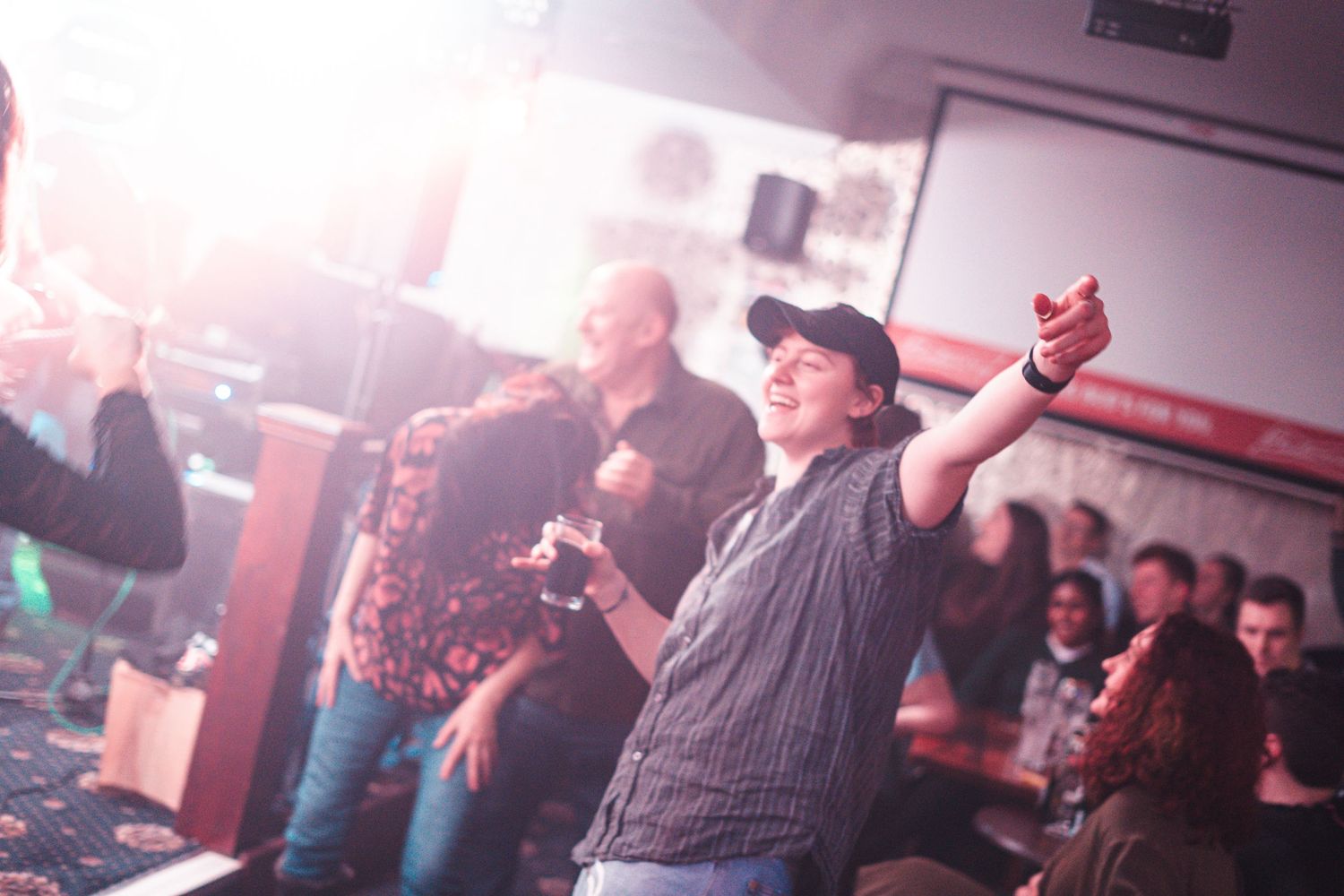 Concert attendee raises arms in celebration during live music performance.