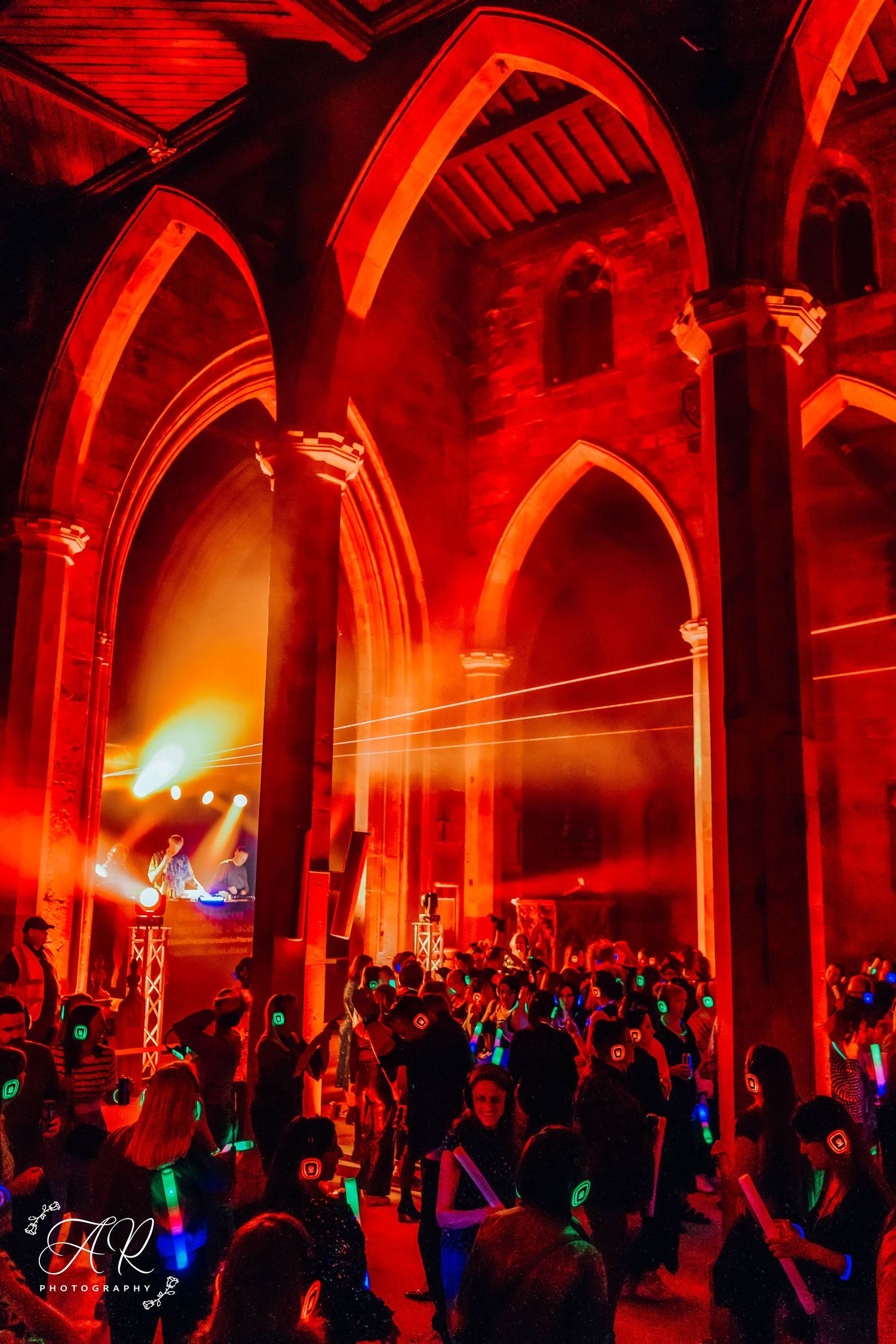 Gothic-style venue bathed in dramatic red lighting during a nighttime music event.