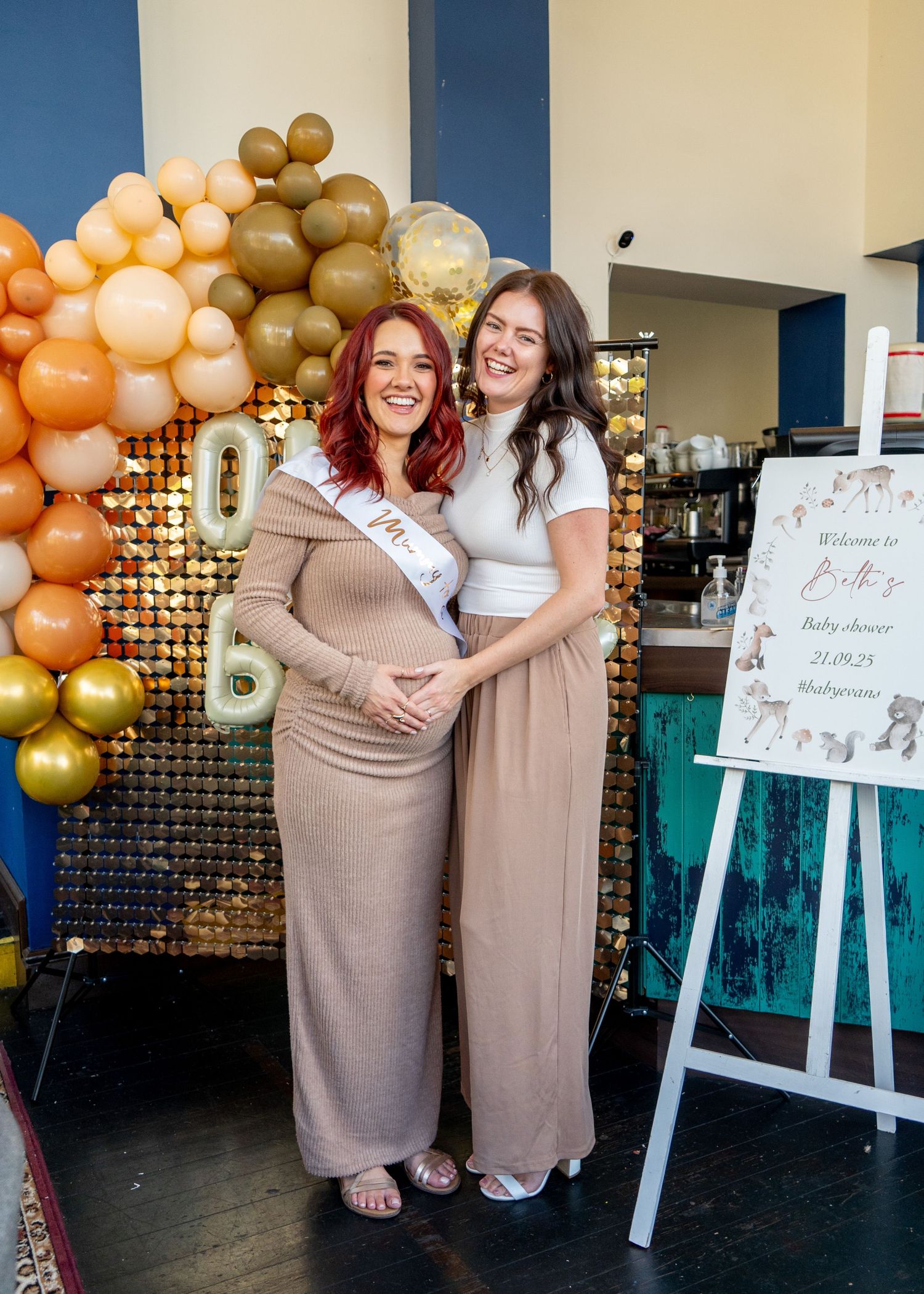 Event space decorated with balloon arch and easels displaying signs as friends celebrate together.