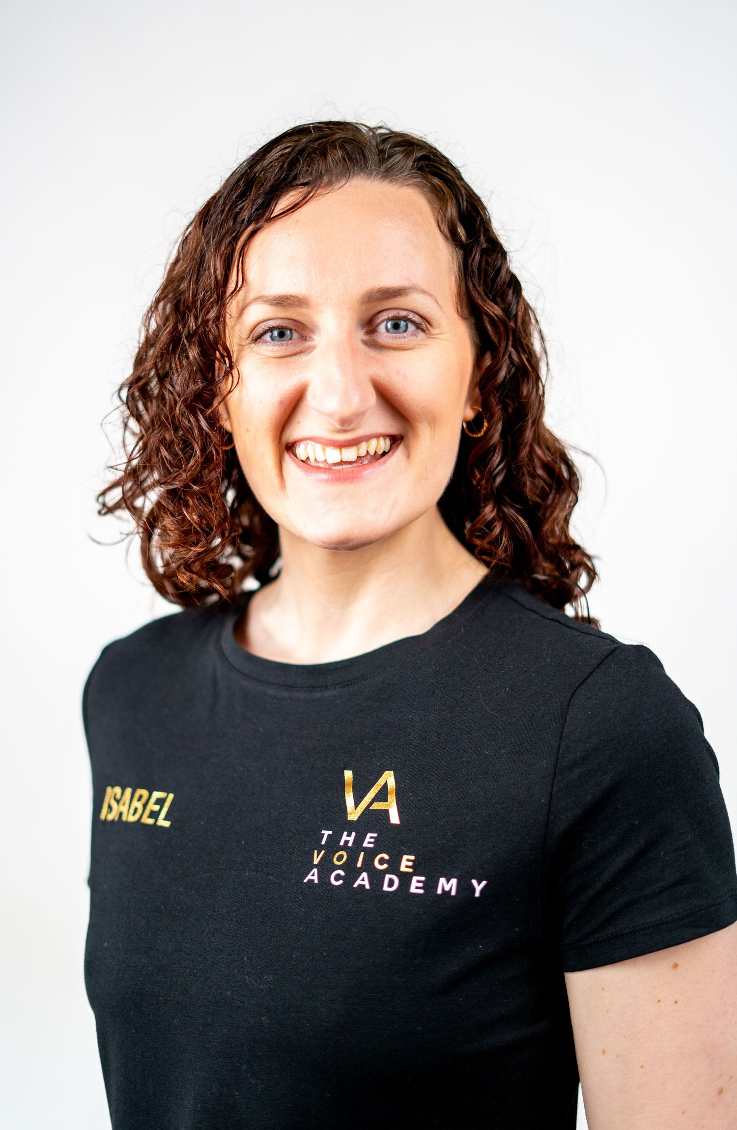 Performer in black t-shirt with academy branding smiles against white background.