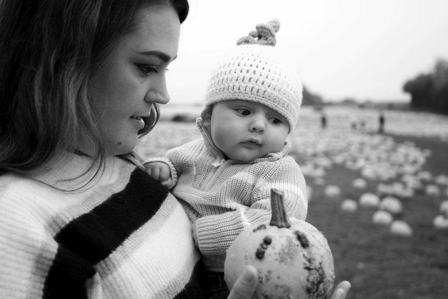 Black and white portrait of tender family moment at autumn pumpkin patch.