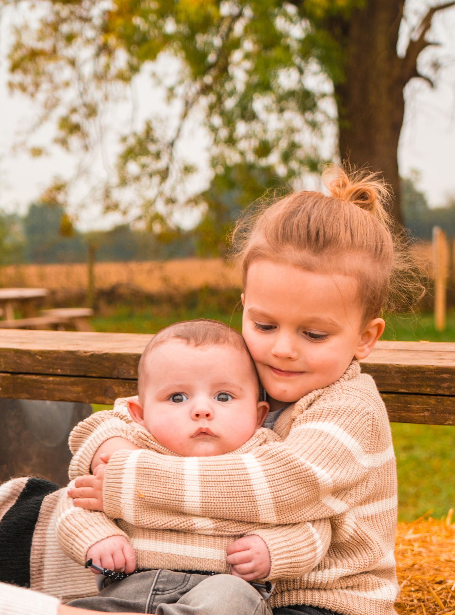 Tender moments shared between siblings in cozy sweaters during fall.