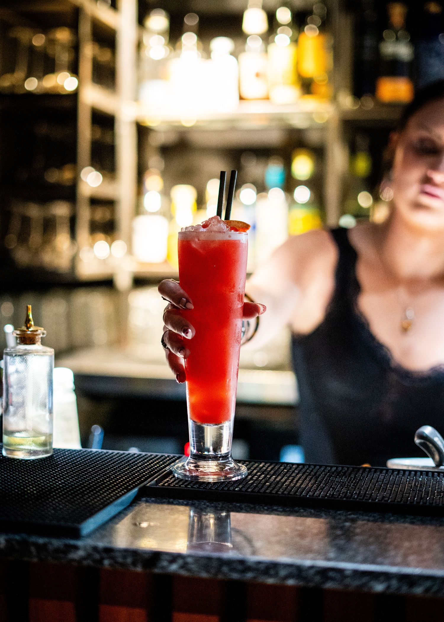 Colorful cocktails lined up on a dark bar counter.